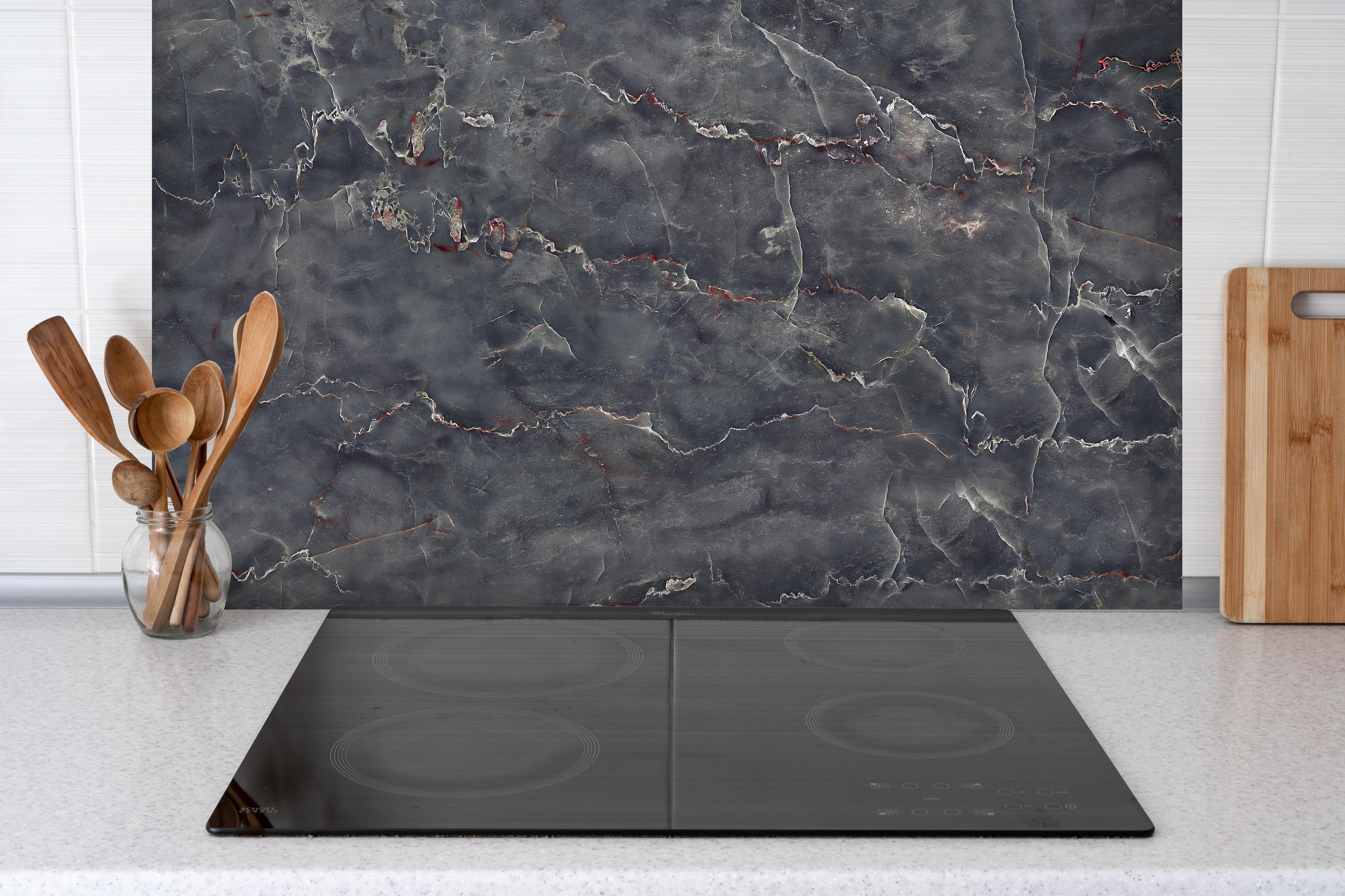 Spritzschutz - Polierter Onyxmarmor mit Adern hinter einem Cerankochfeld zwischen Holz-Kochutensilien