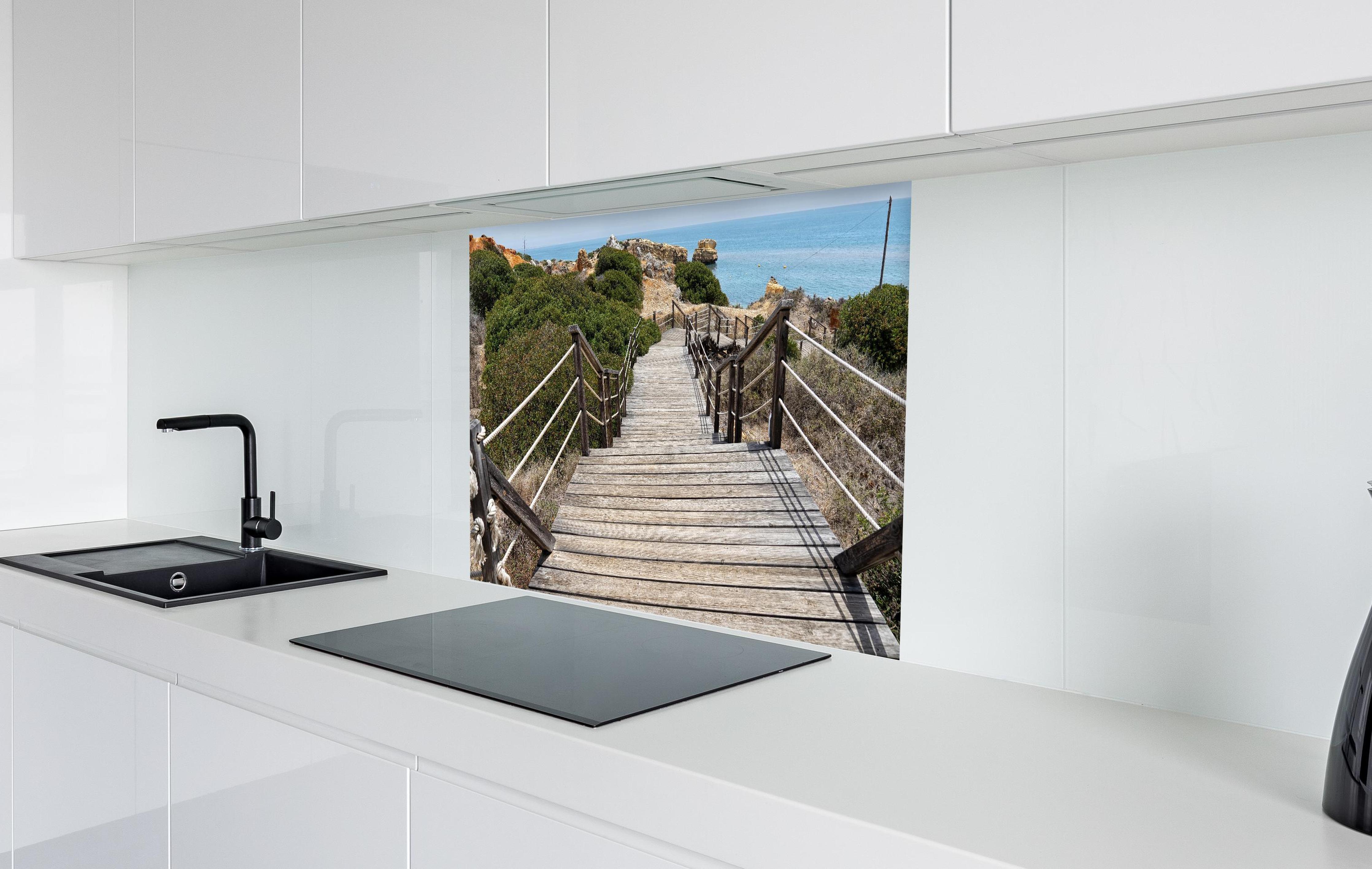 Spritzschutz - Portugal Küstenlinie in weißer Hochglanz-Küche hinter einem Cerankochfeld