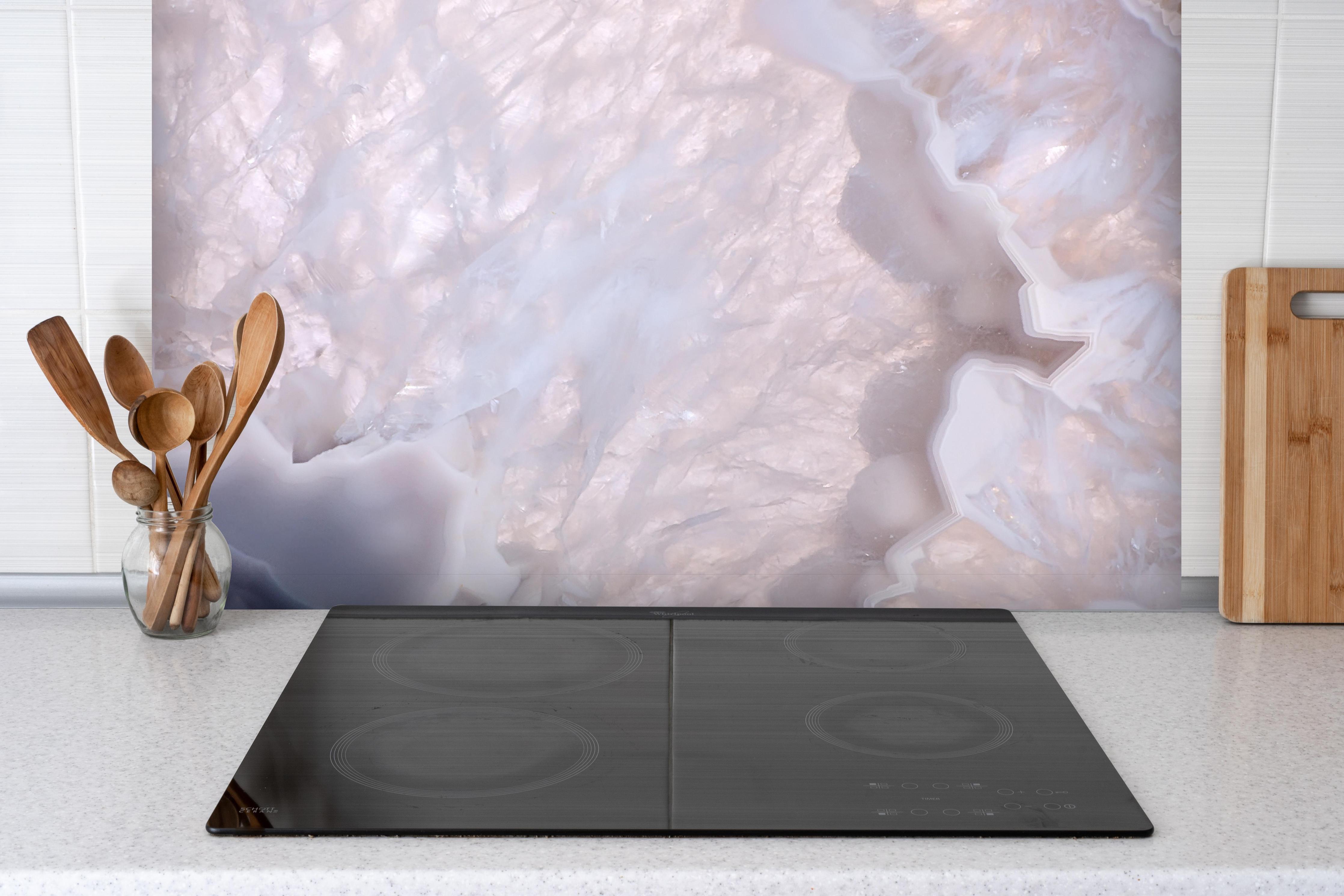 Spritzschutz - Quarz in Wellenstruktur hinter einem Cerankochfeld zwischen Holz-Kochutensilien