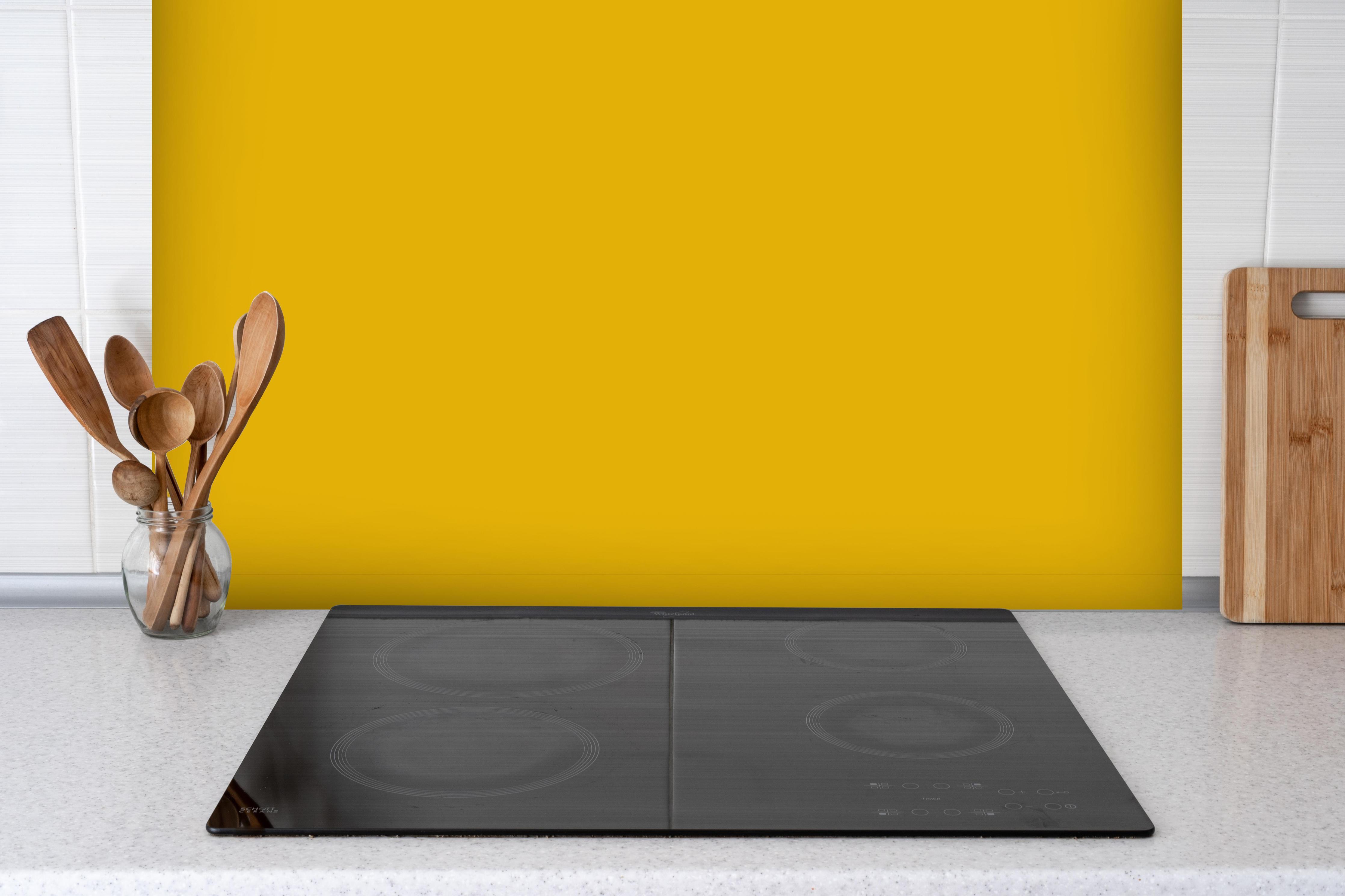 Spritzschutz - RAL 1004 (Goldgelb) hinter einem Cerankochfeld zwischen Holz-Kochutensilien