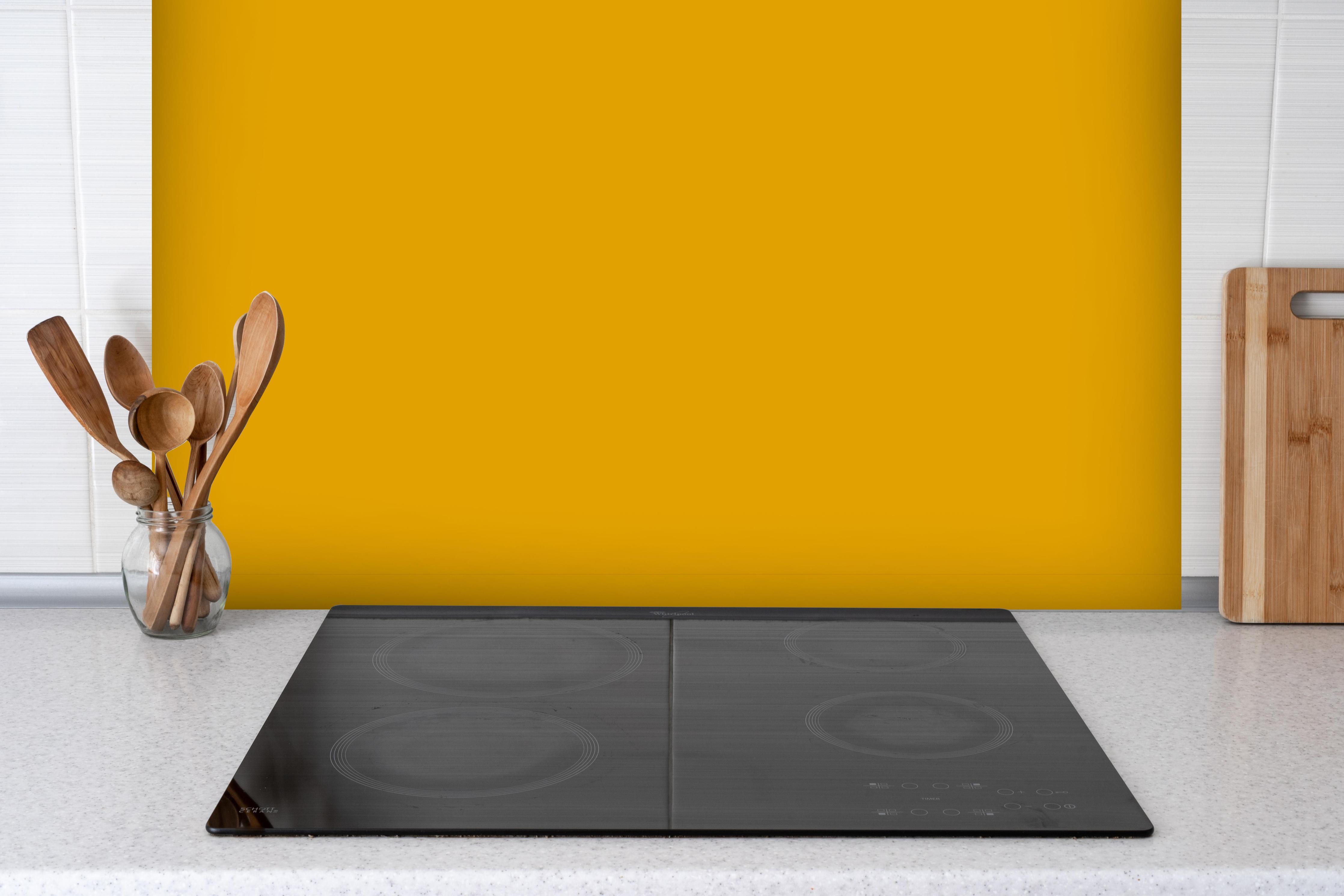 Spritzschutz - RAL 1006 (Maisgelb) hinter einem Cerankochfeld zwischen Holz-Kochutensilien