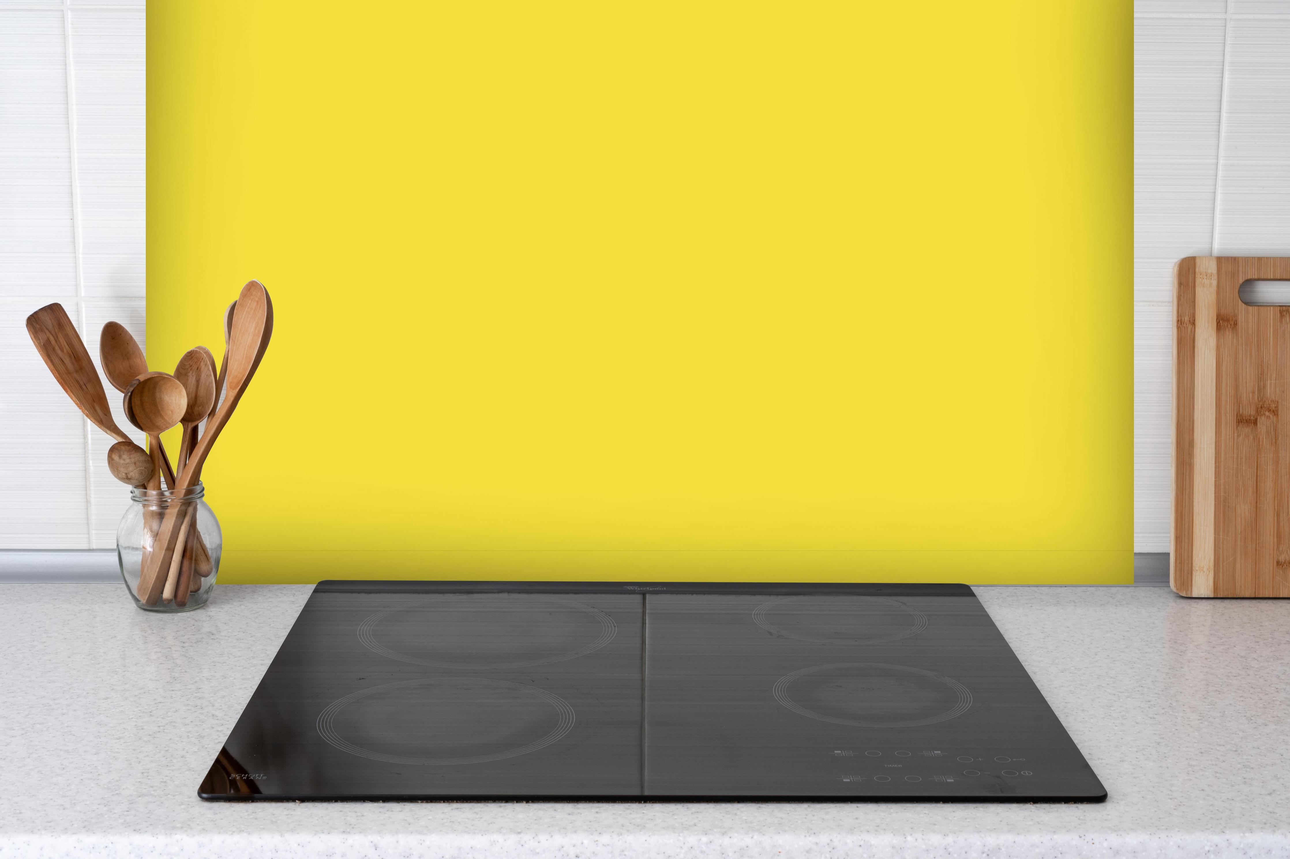 Spritzschutz - RAL 1018 (Zinkgelb) hinter einem Cerankochfeld zwischen Holz-Kochutensilien