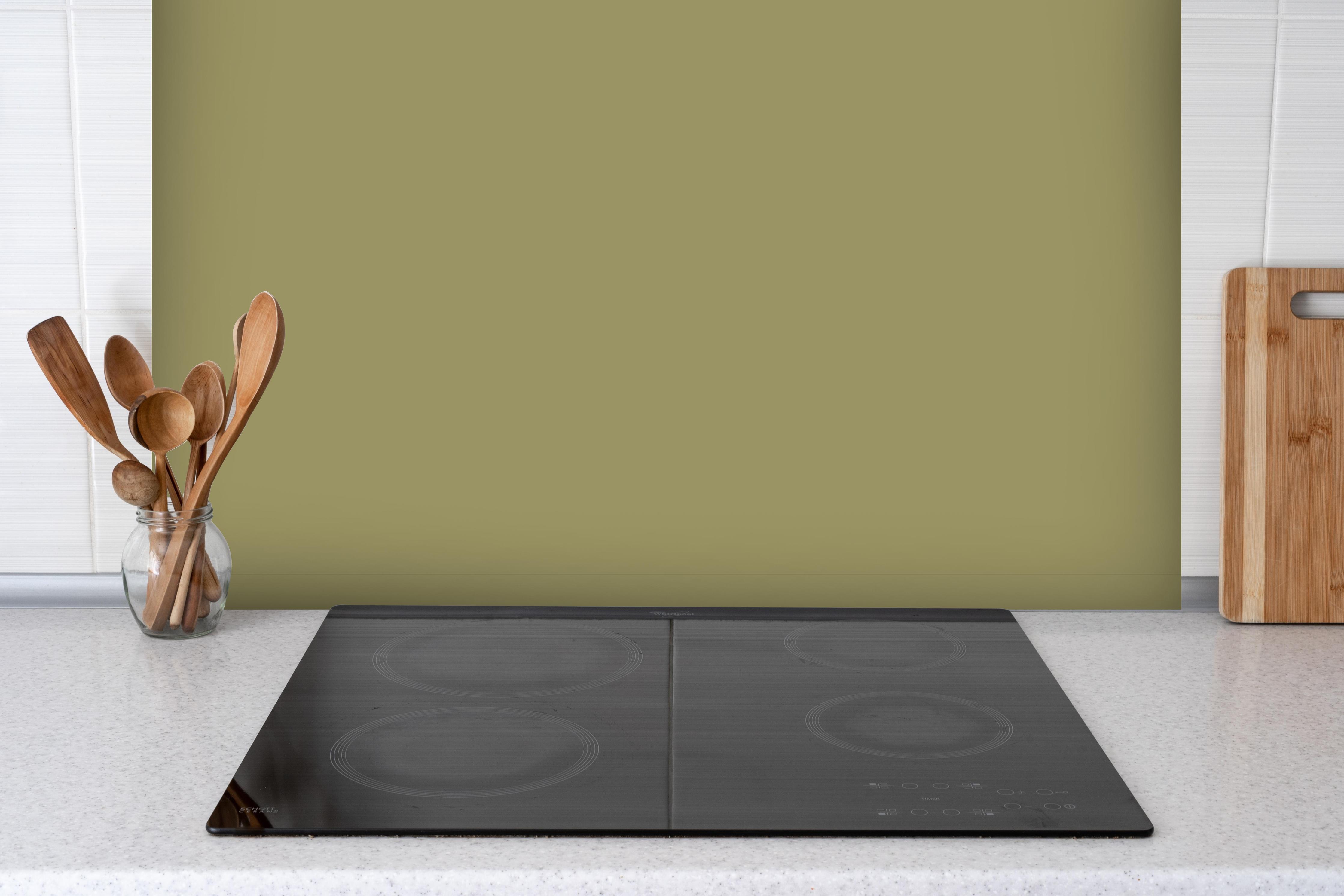 Spritzschutz - RAL 1020 (olivgelb) hinter einem Cerankochfeld zwischen Holz-Kochutensilien