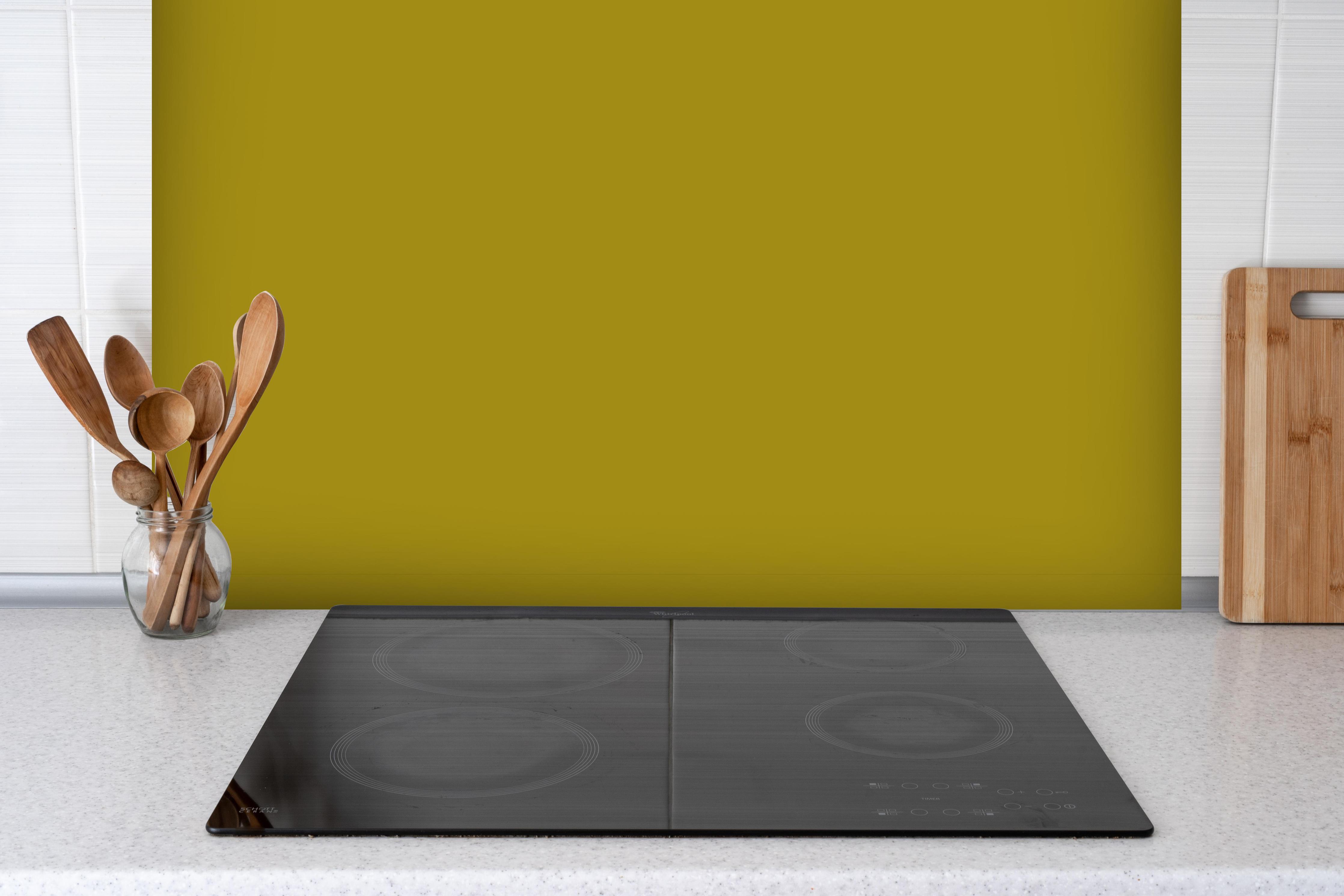 Spritzschutz - RAL 1027 (Curry) hinter einem Cerankochfeld zwischen Holz-Kochutensilien