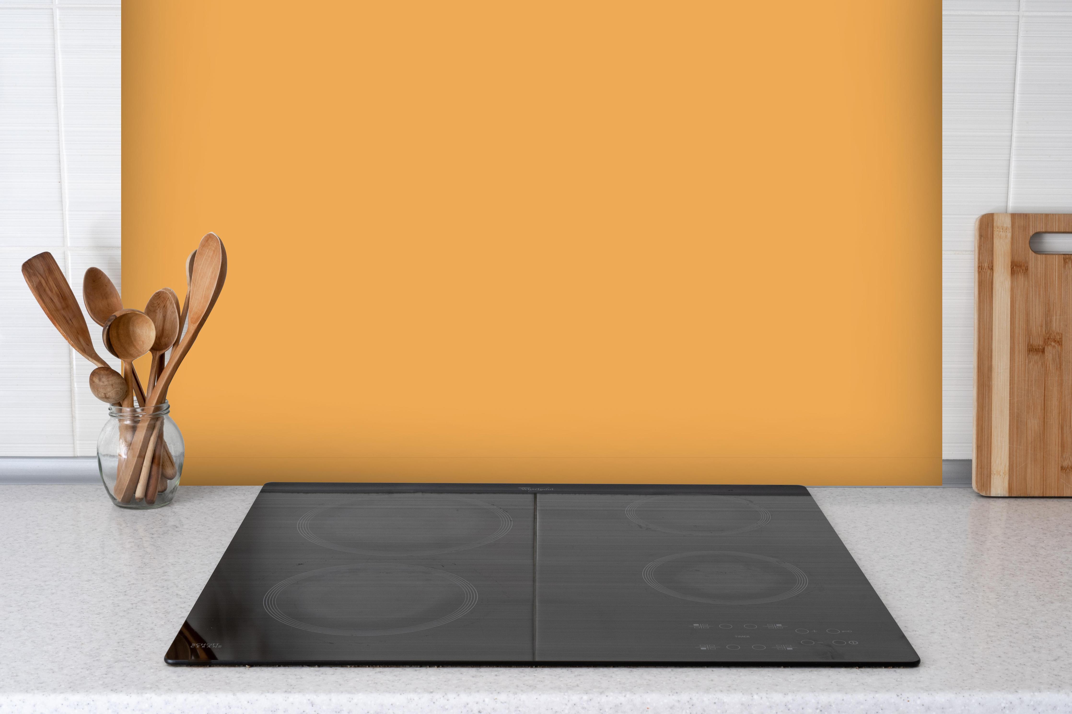 Spritzschutz - RAL 1034 (Pastellgelb) hinter einem Cerankochfeld zwischen Holz-Kochutensilien