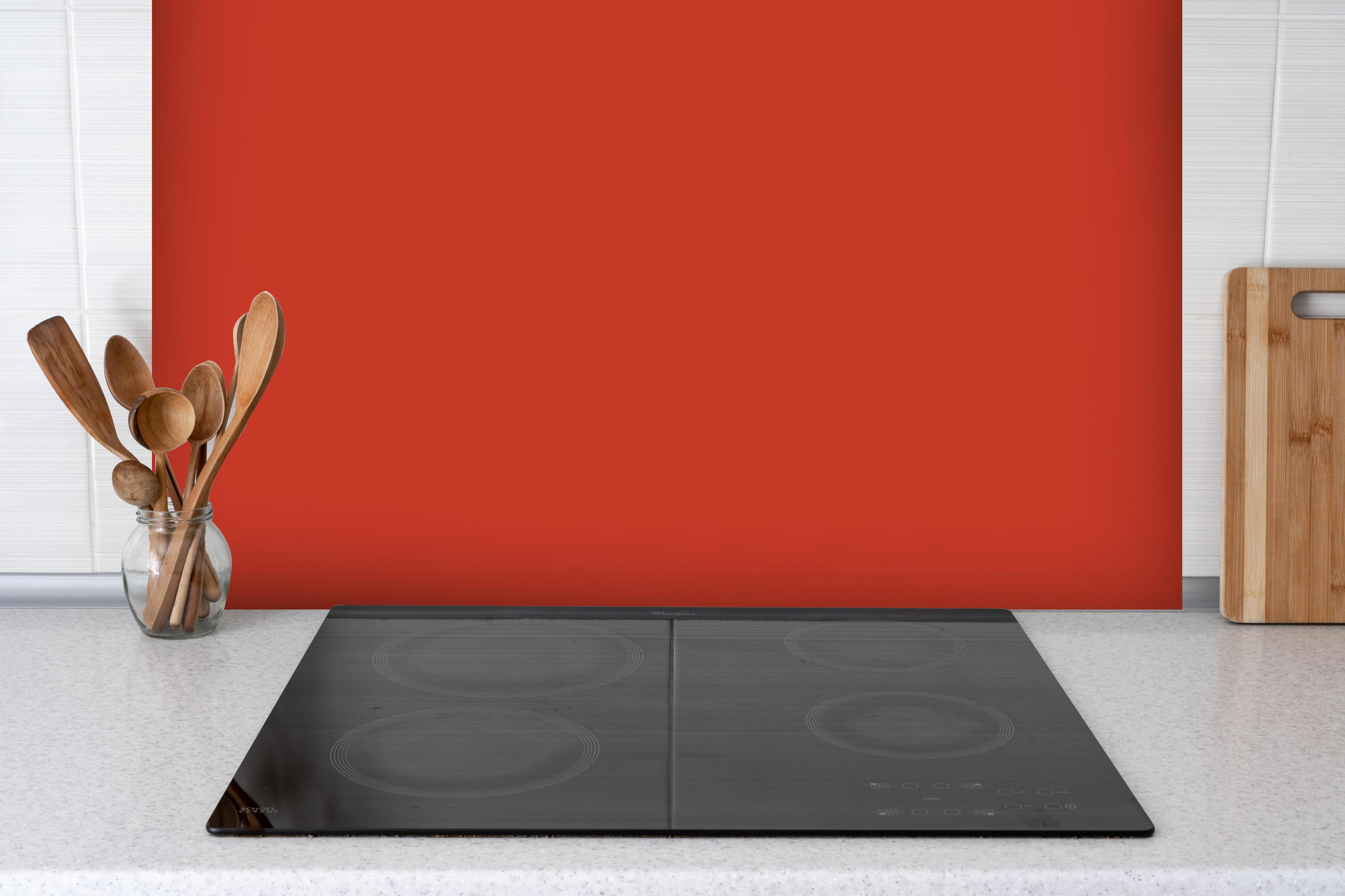 Spritzschutz - RAL 2002 (Zinnoberrot) hinter einem Cerankochfeld zwischen Holz-Kochutensilien