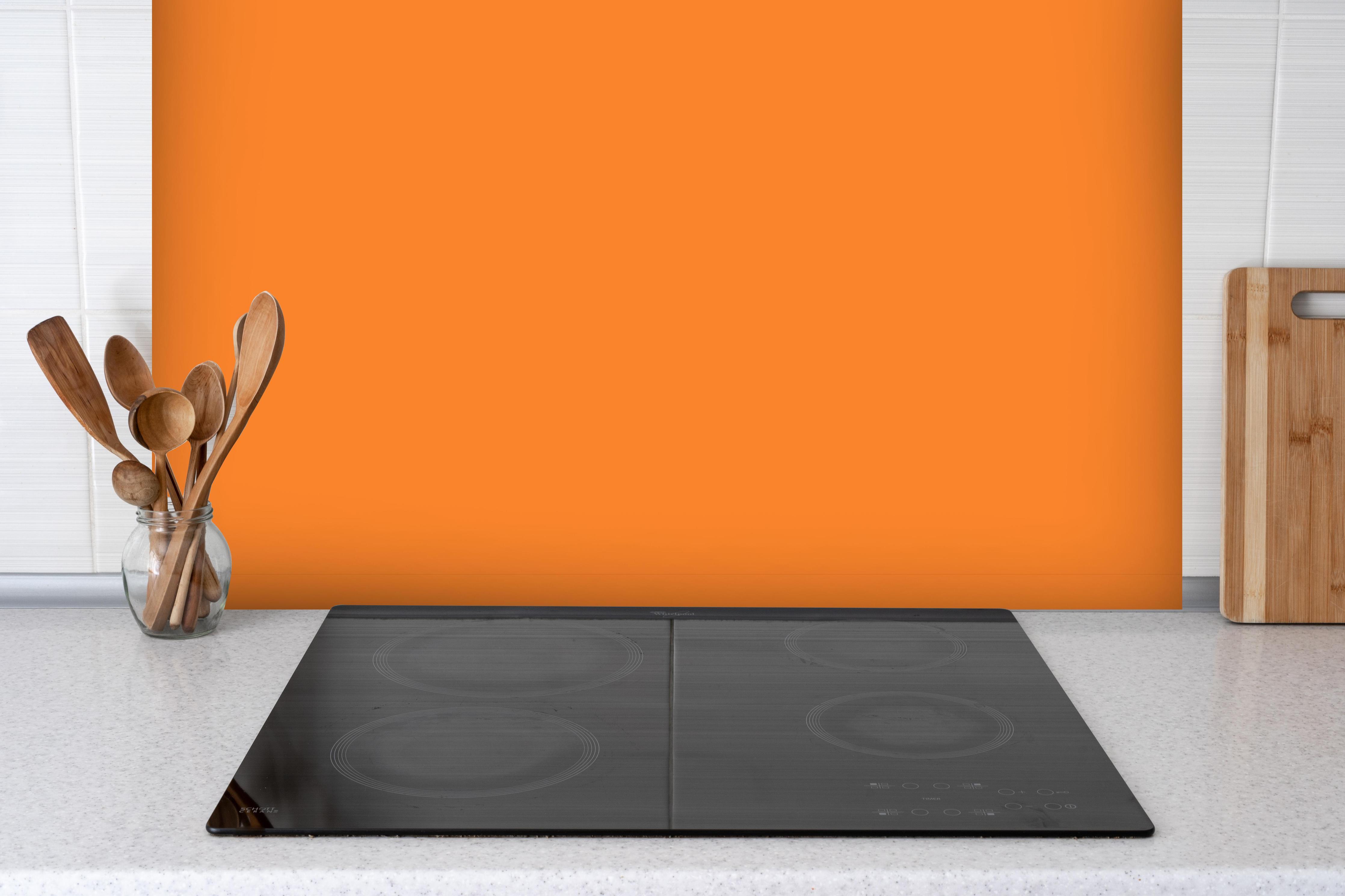 Spritzschutz - RAL 2003 (Pastellorange) hinter einem Cerankochfeld zwischen Holz-Kochutensilien