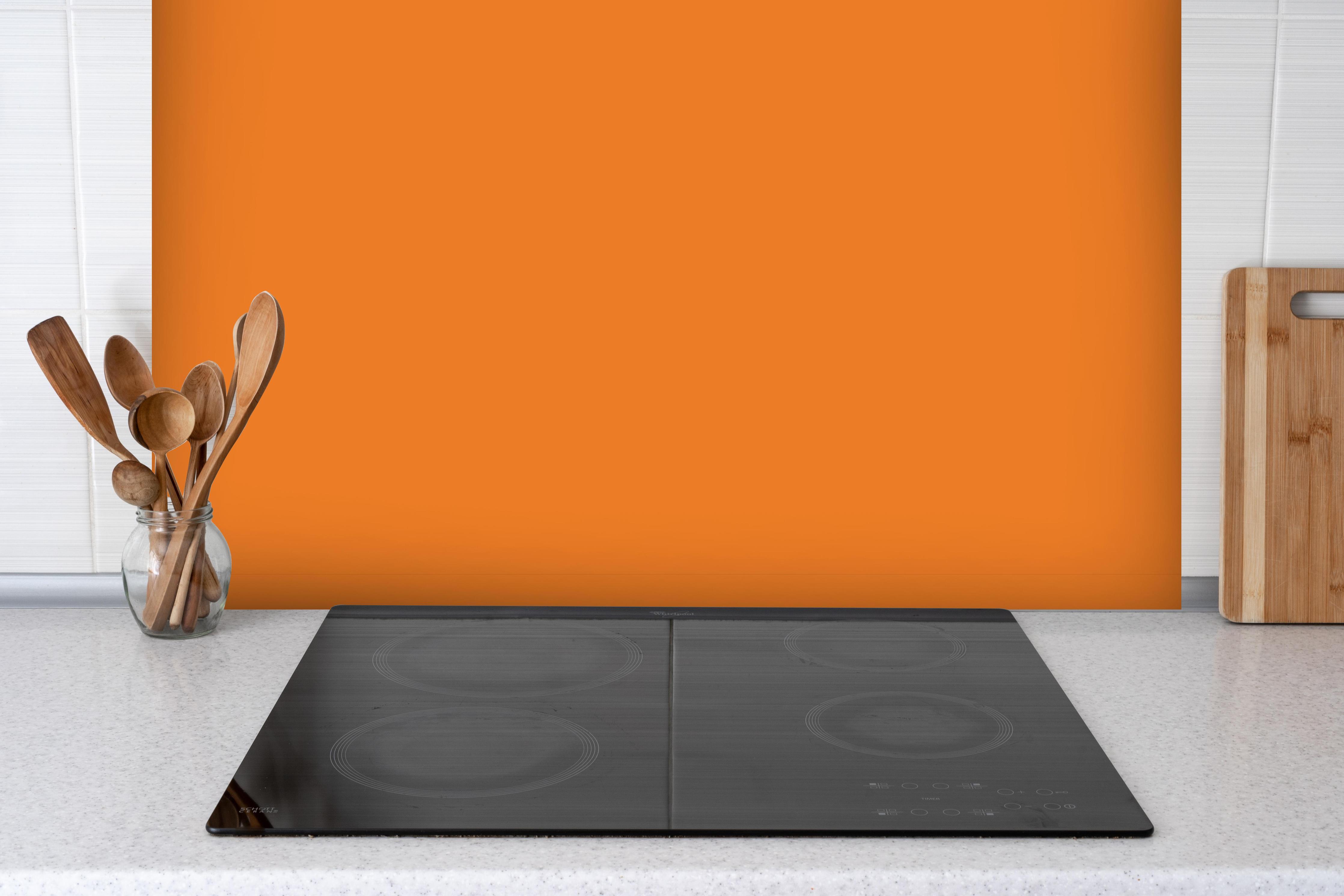 Spritzschutz - RAL 2011 (Tieforange) hinter einem Cerankochfeld zwischen Holz-Kochutensilien