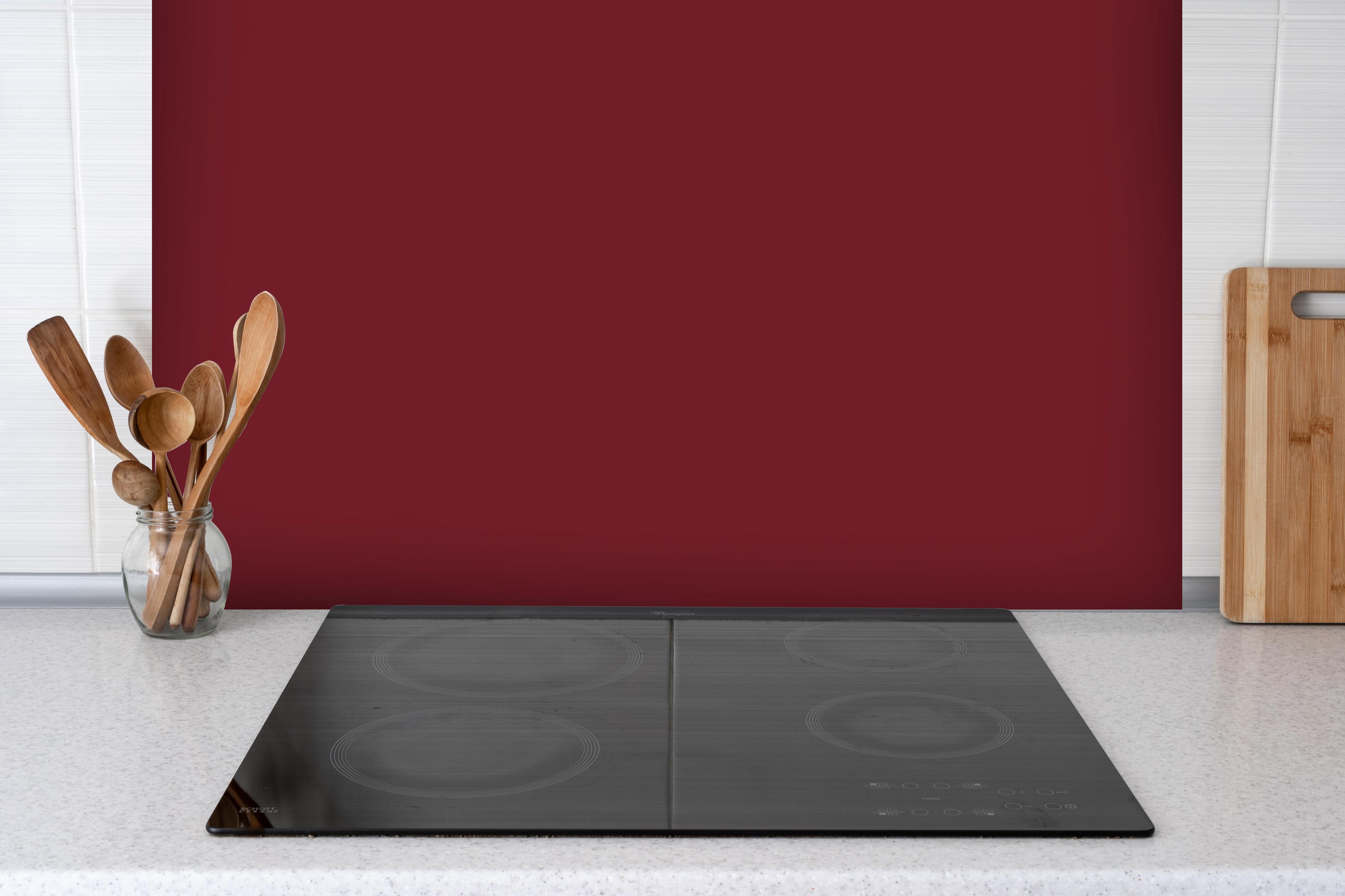 Spritzschutz - RAL 3004 (Purpurrot) hinter einem Cerankochfeld zwischen Holz-Kochutensilien