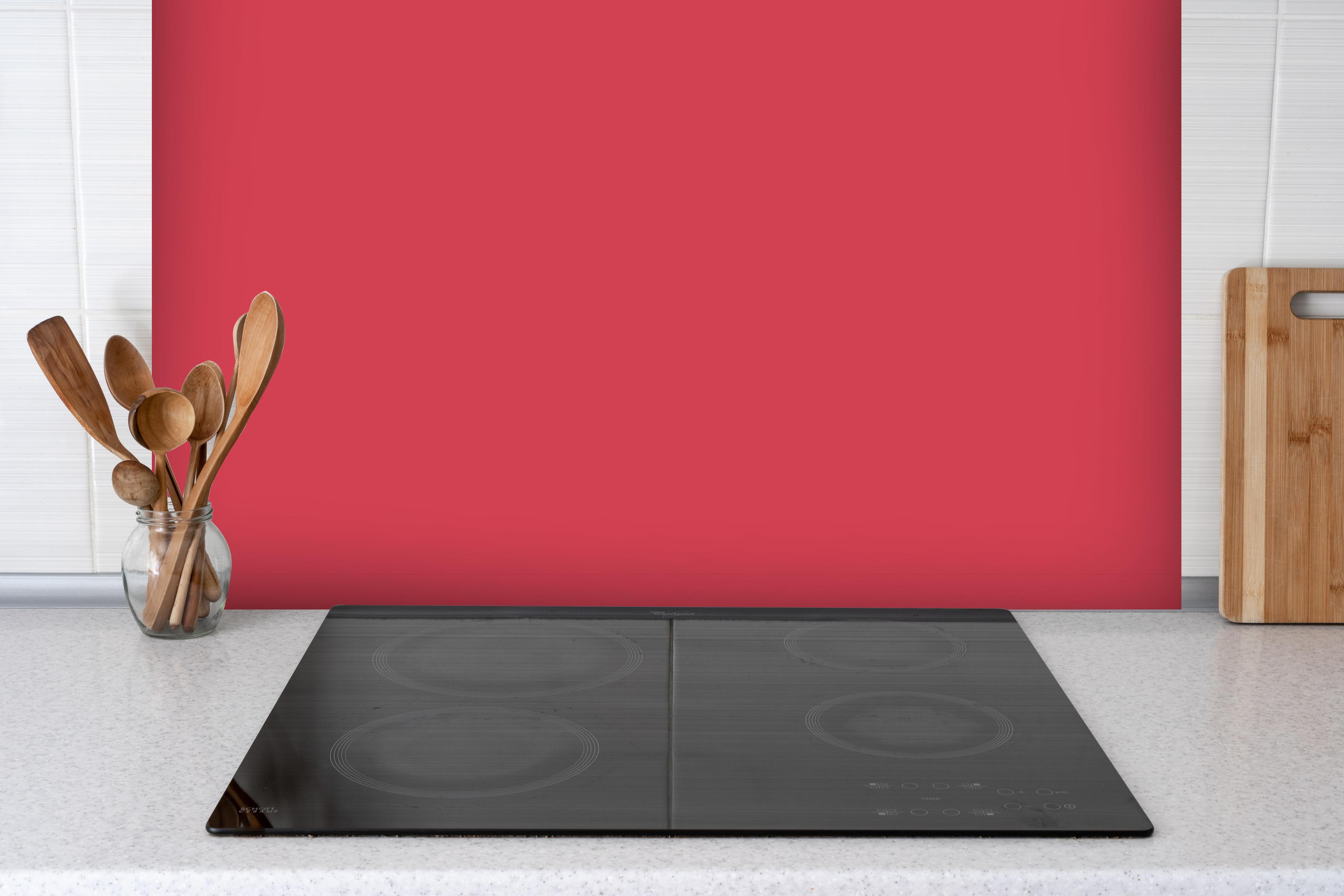 Spritzschutz - RAL 3018 (erdbeerrot) hinter einem Cerankochfeld zwischen Holz-Kochutensilien