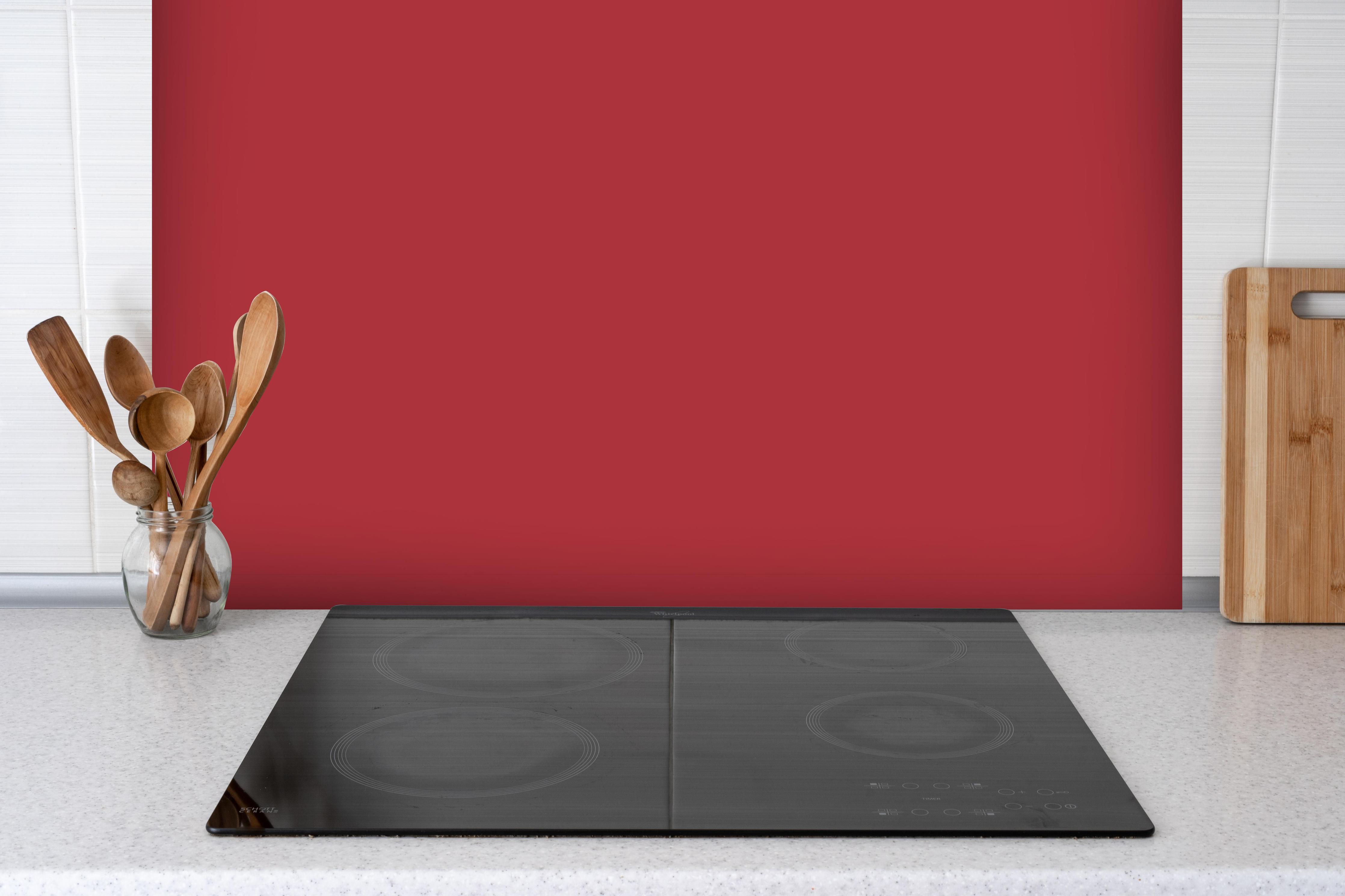 Spritzschutz - RAL 3031 (Orientrot) hinter einem Cerankochfeld zwischen Holz-Kochutensilien