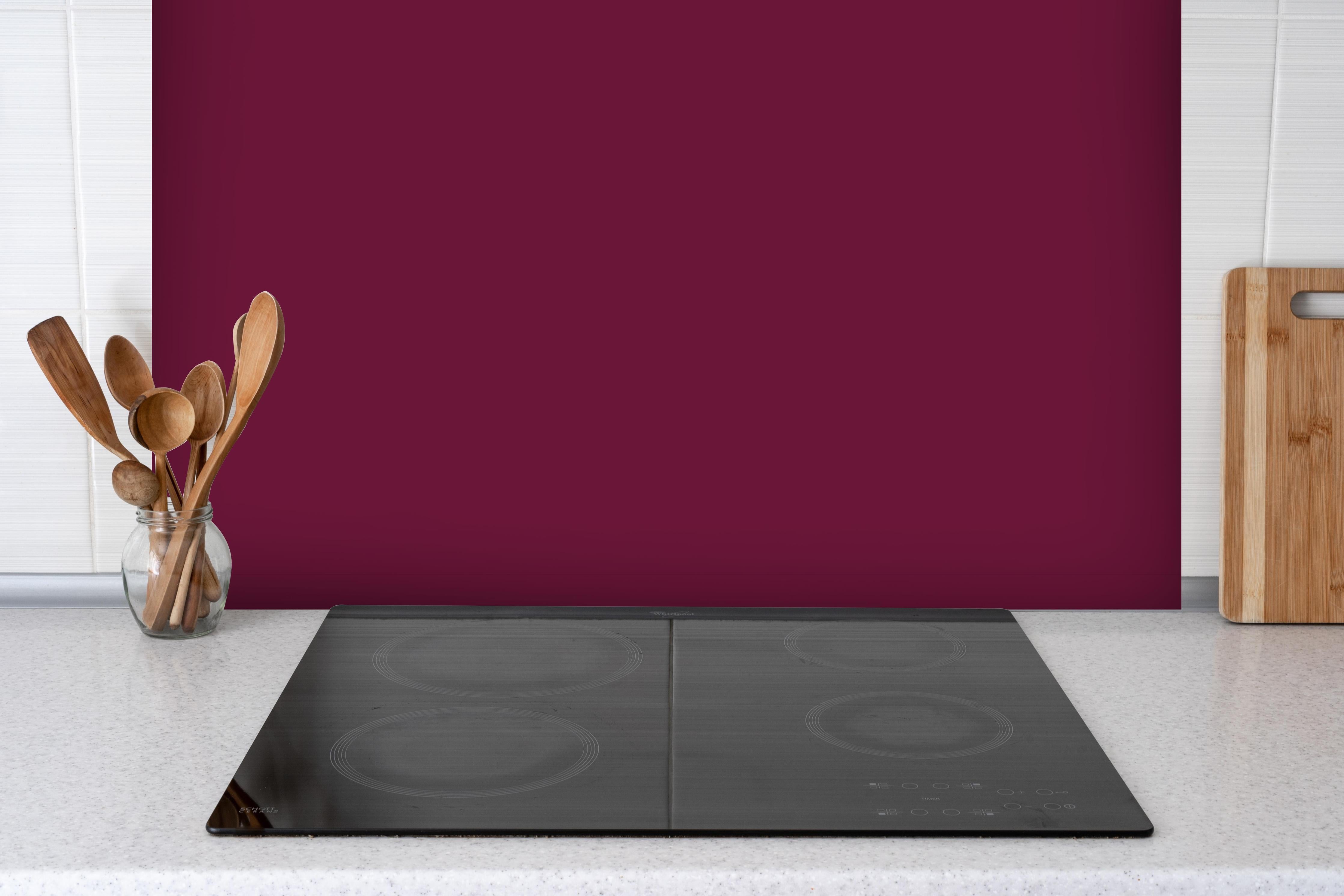 Spritzschutz - RAL 4004 (Weinrotviolett) hinter einem Cerankochfeld zwischen Holz-Kochutensilien