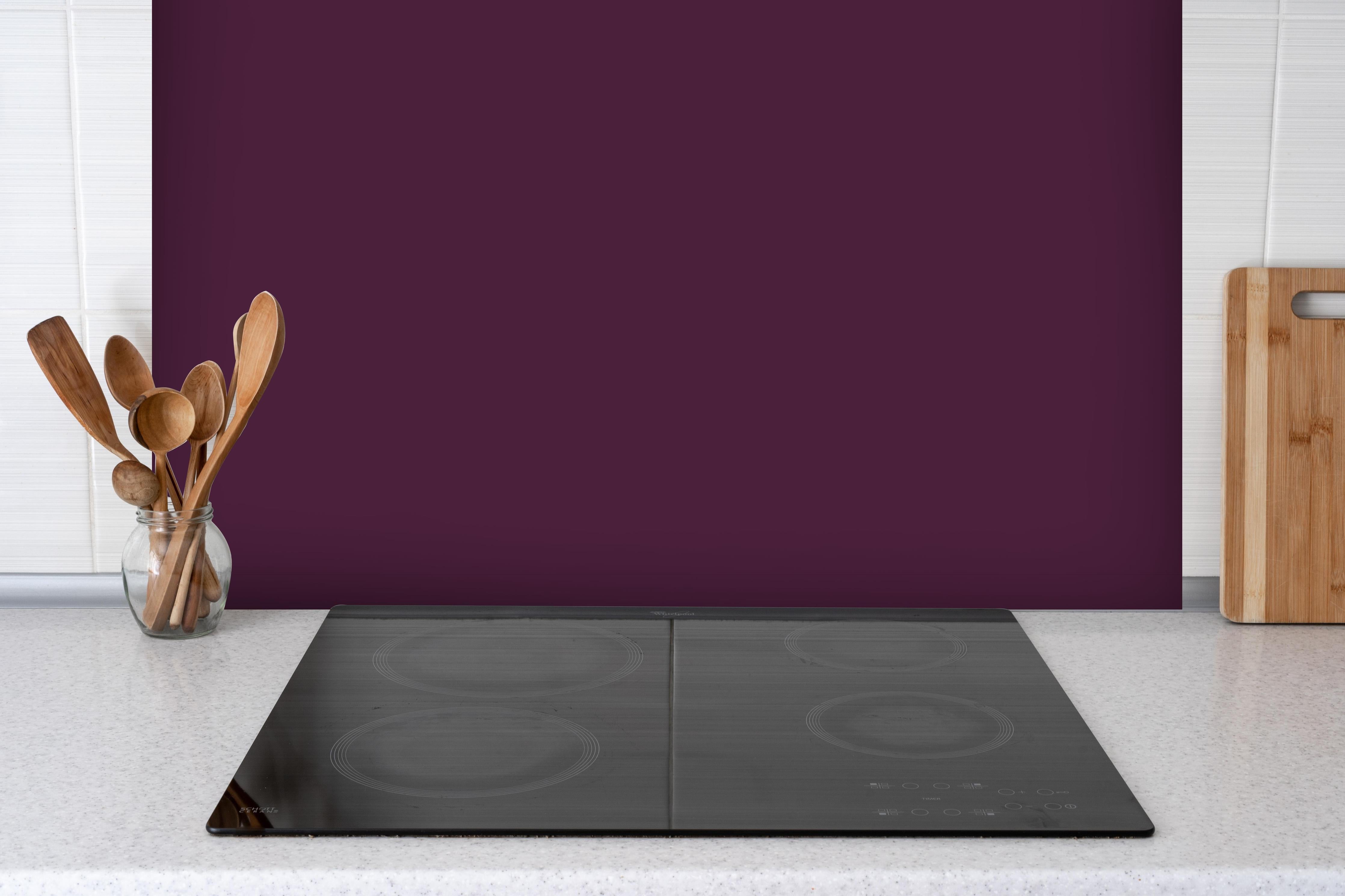 Spritzschutz - RAL 4007 (Purpurviolett) hinter einem Cerankochfeld zwischen Holz-Kochutensilien