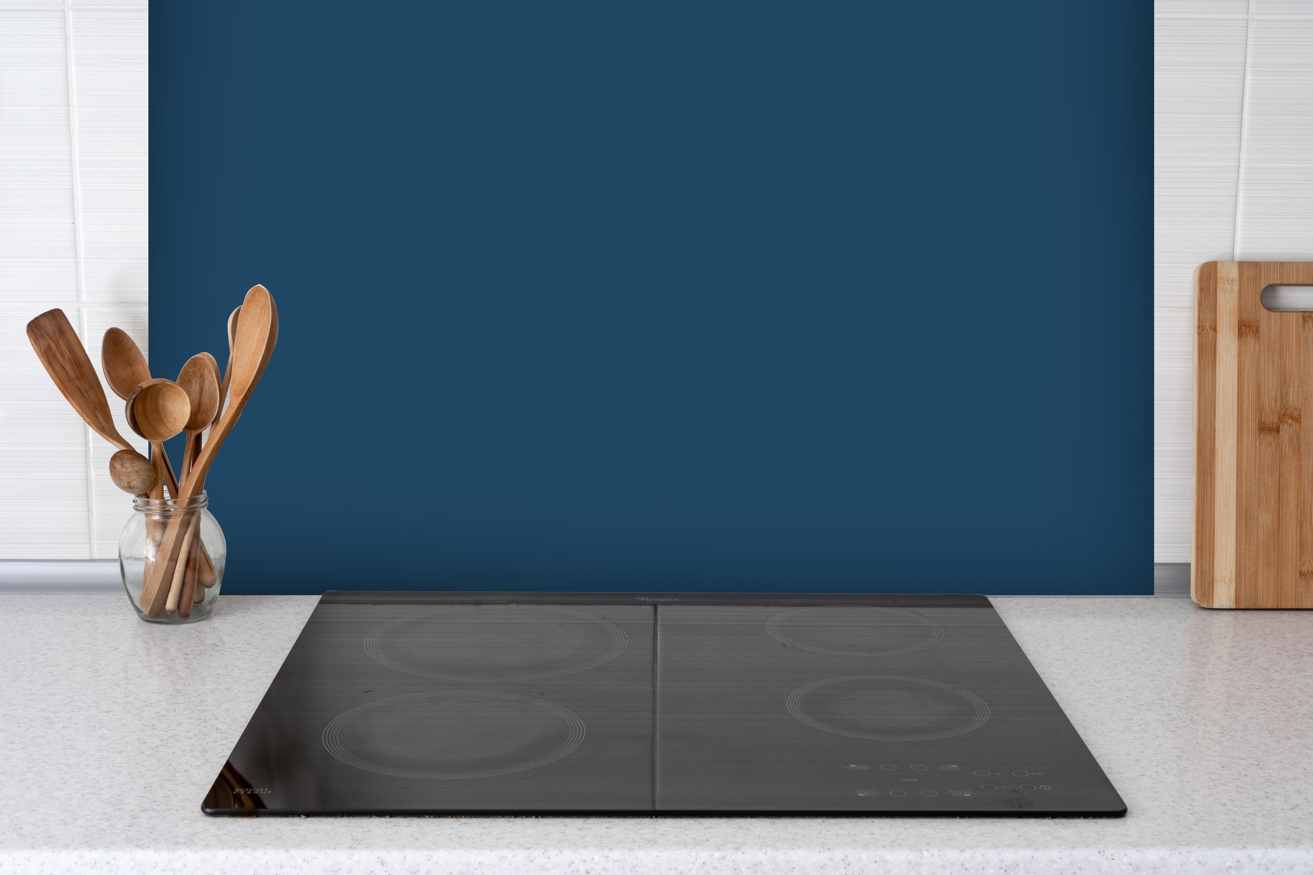 Spritzschutz - RAL 5001 (Grünblau) hinter einem Cerankochfeld zwischen Holz-Kochutensilien