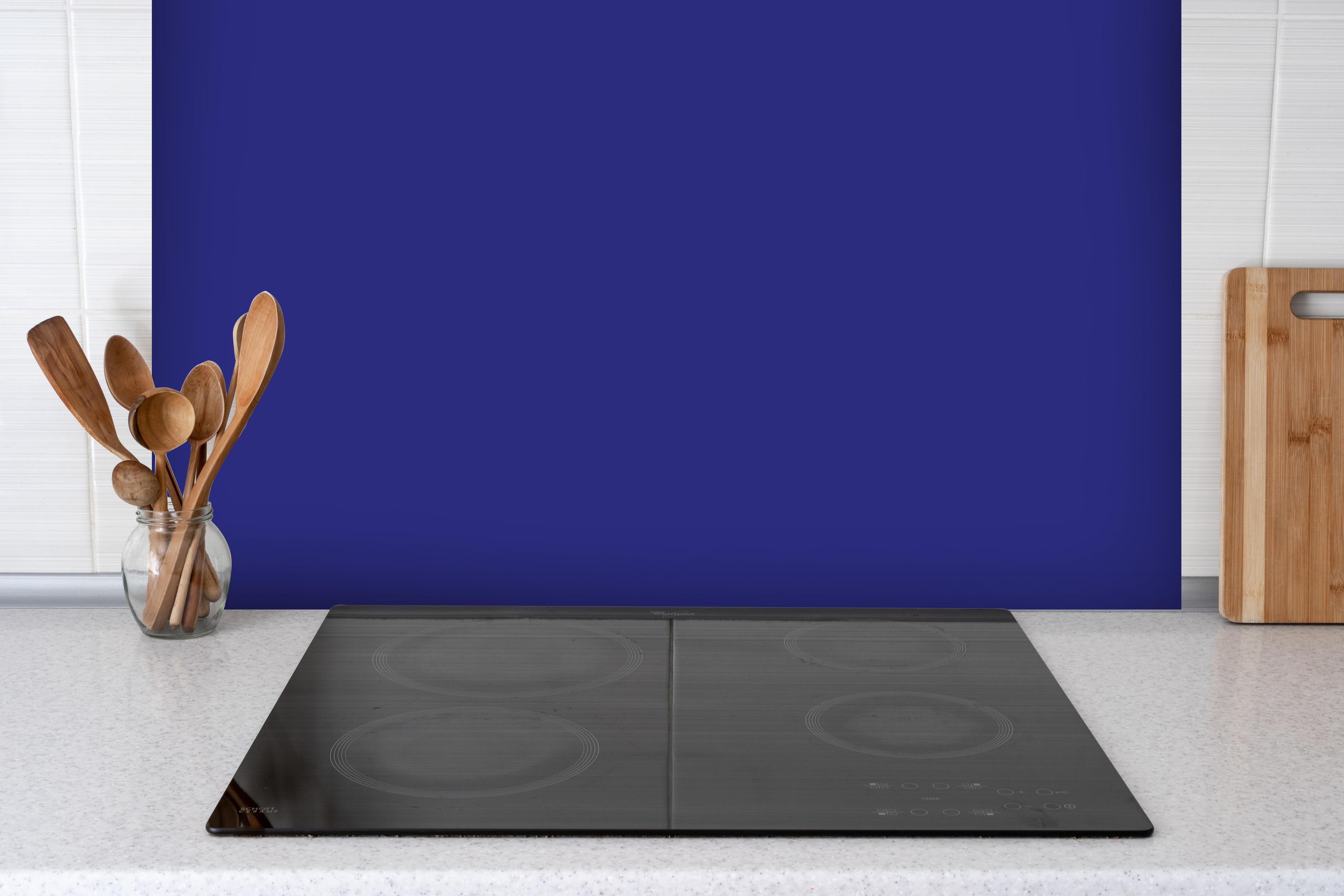 Spritzschutz - RAL 5002 (Ultramarinblau) hinter einem Cerankochfeld zwischen Holz-Kochutensilien