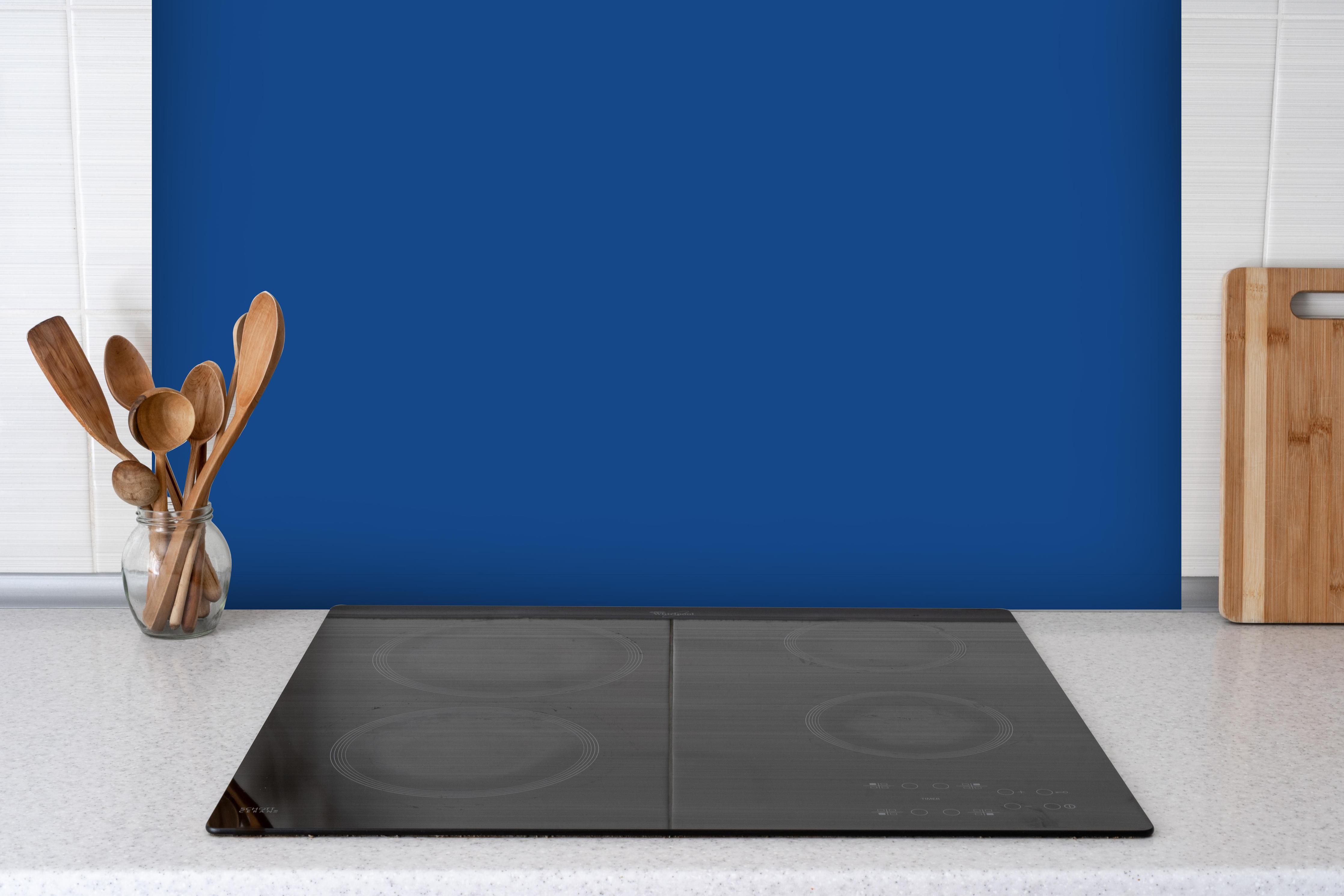 Spritzschutz - RAL 5005 (Signalblau) hinter einem Cerankochfeld zwischen Holz-Kochutensilien