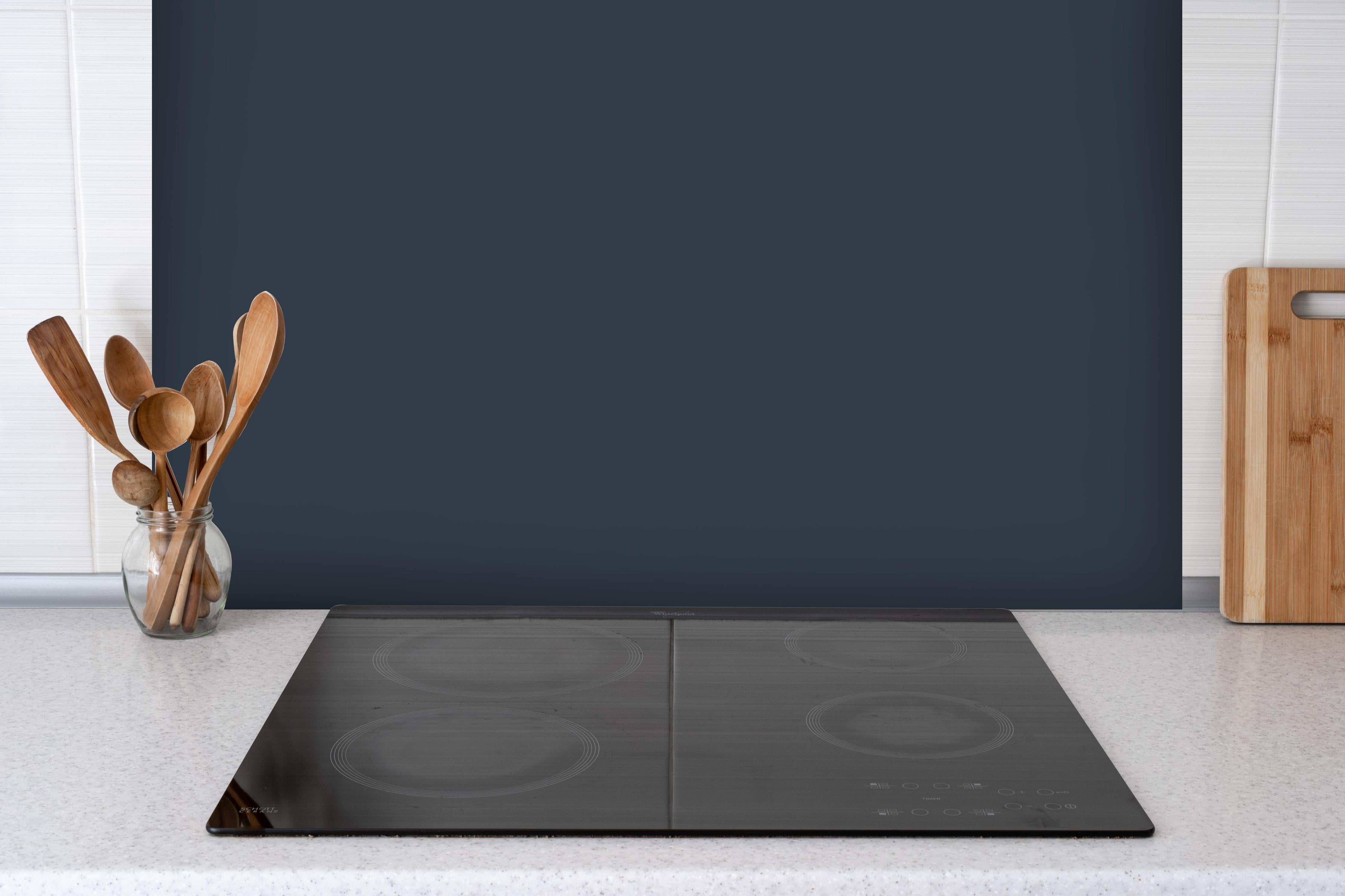 Spritzschutz - RAL 5008 (Graublau) hinter einem Cerankochfeld zwischen Holz-Kochutensilien