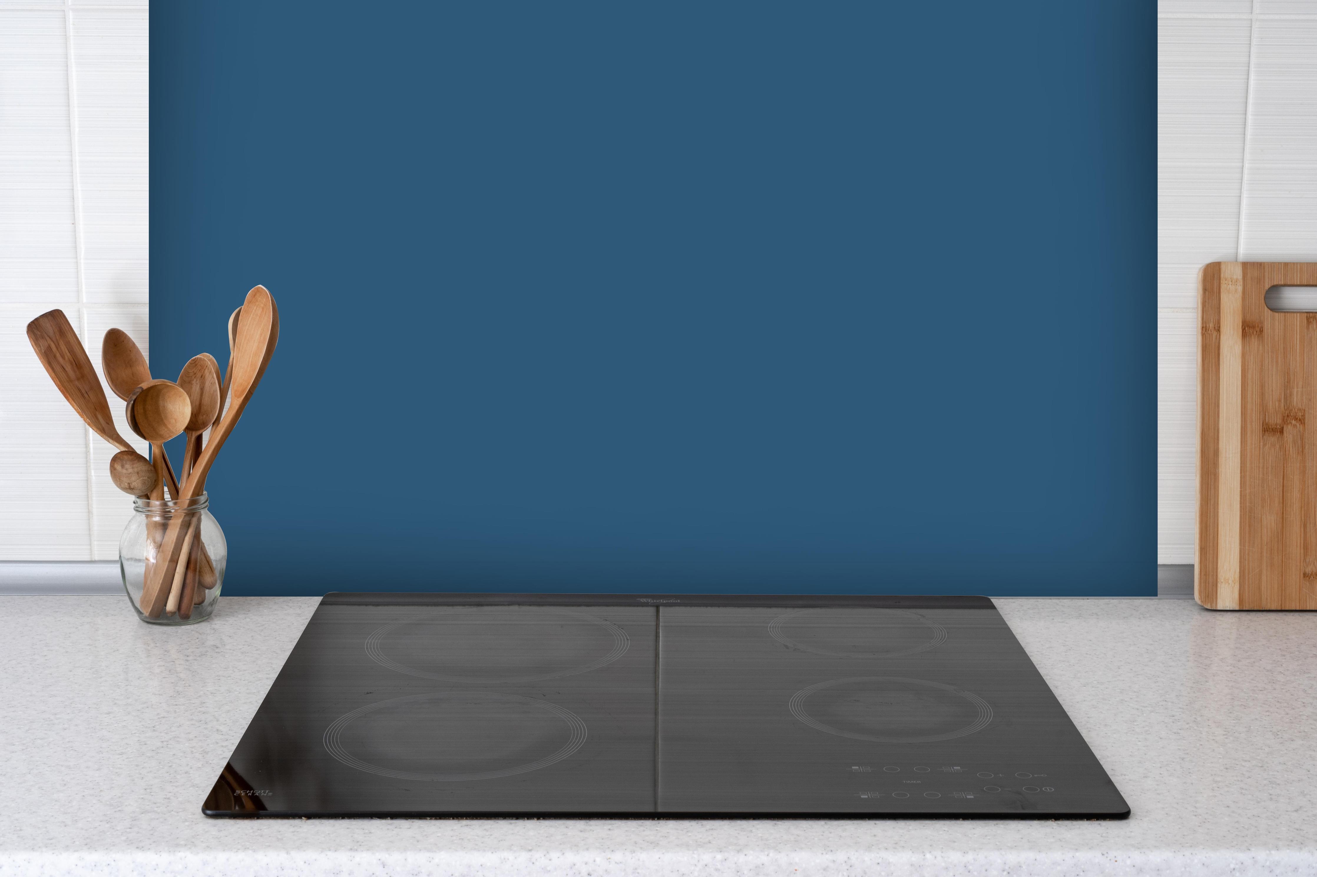 Spritzschutz - RAL 5009 (Azurblau) hinter einem Cerankochfeld zwischen Holz-Kochutensilien