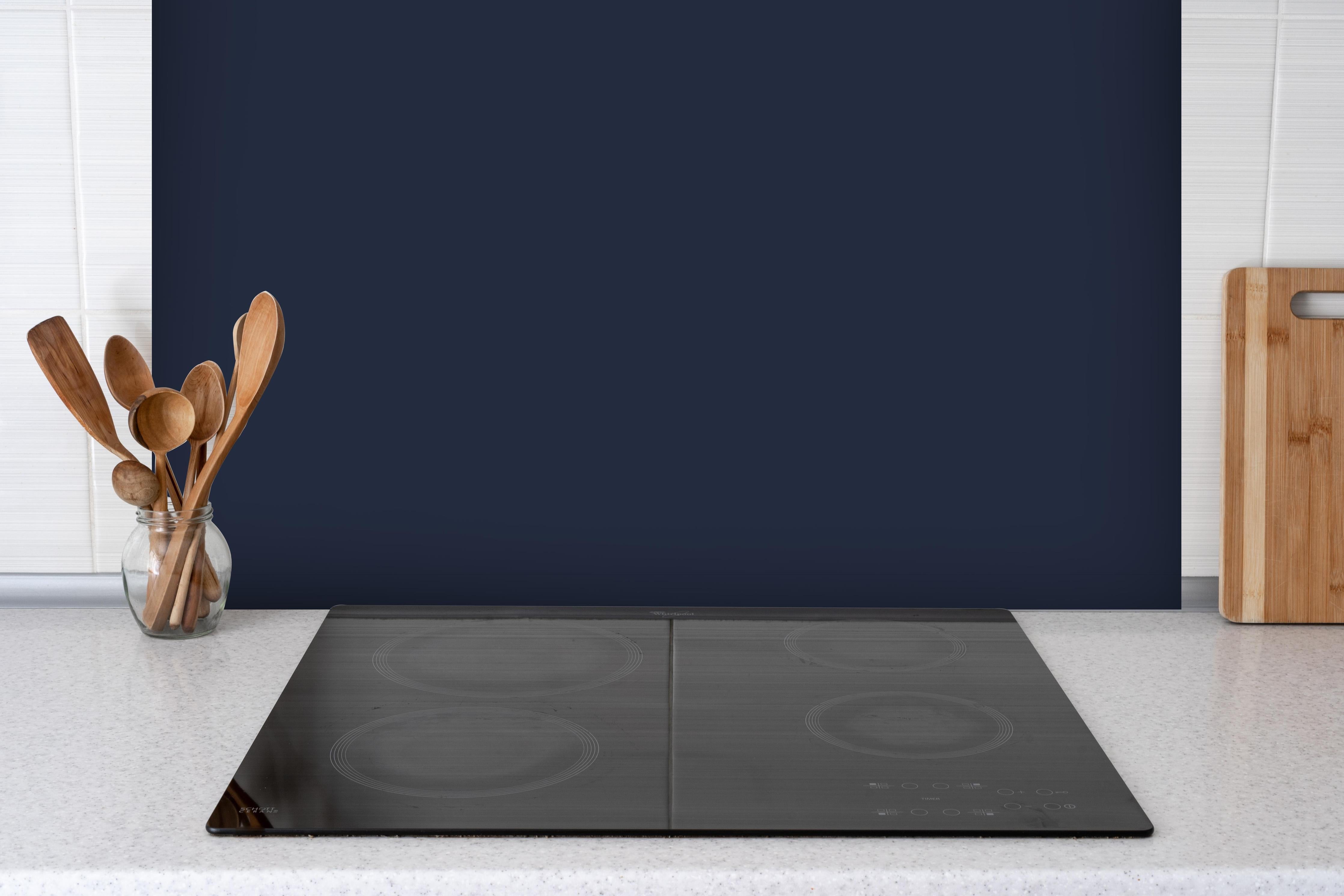 Spritzschutz - RAL 5011 (Stahlblau) hinter einem Cerankochfeld zwischen Holz-Kochutensilien