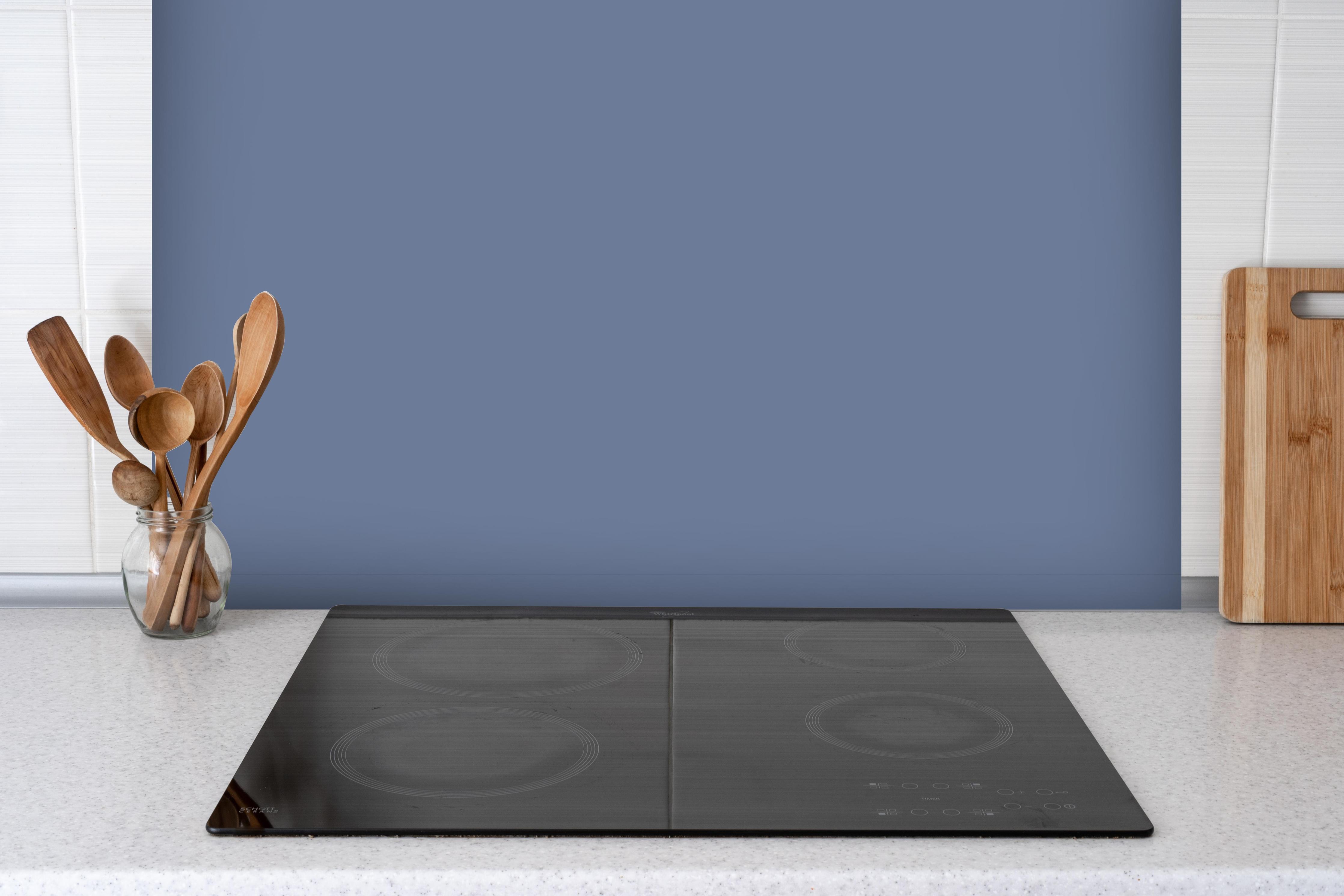 Spritzschutz - RAL 5014 (Taubenblau) hinter einem Cerankochfeld zwischen Holz-Kochutensilien