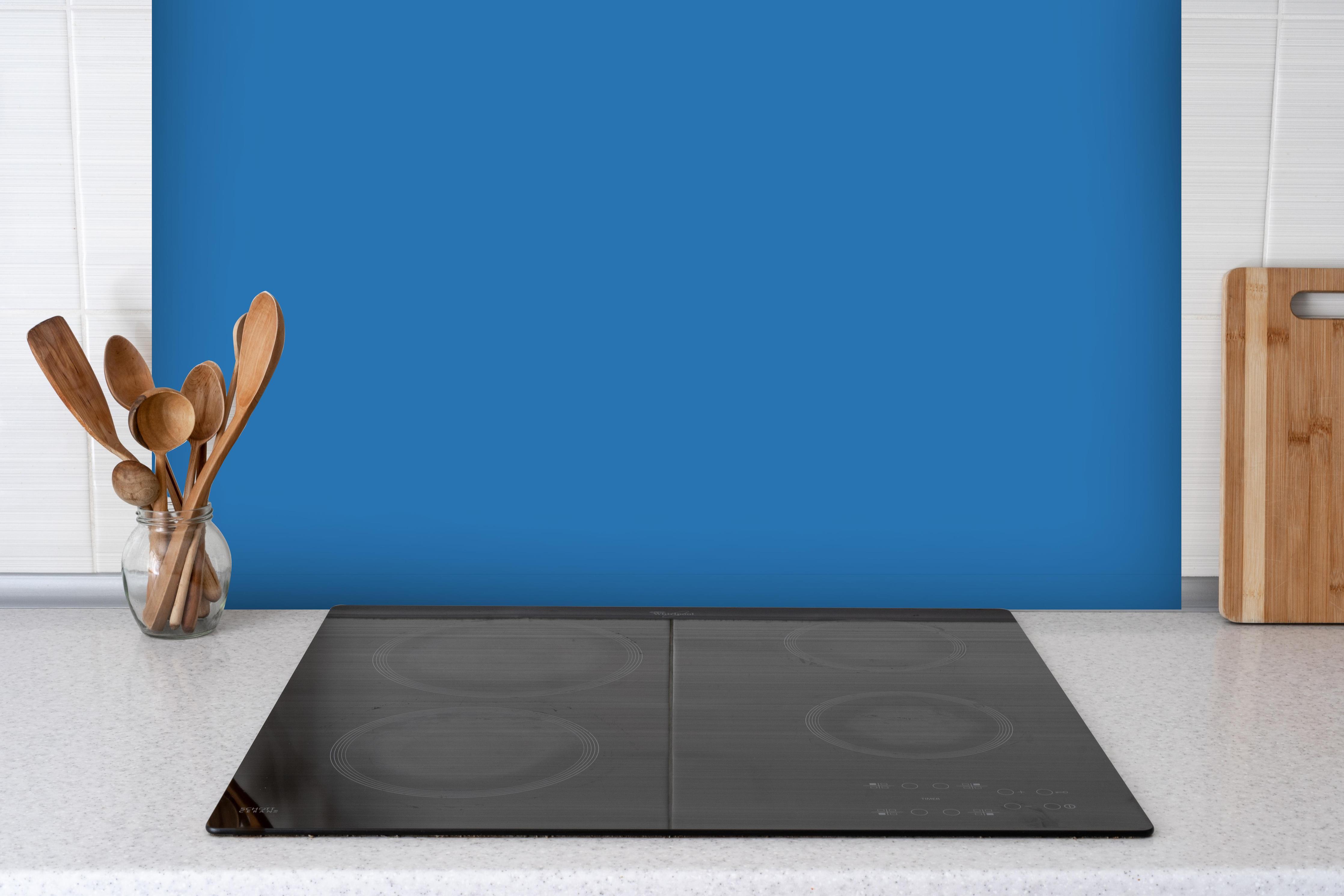 Spritzschutz - RAL 5015 (Himmelblau) hinter einem Cerankochfeld zwischen Holz-Kochutensilien