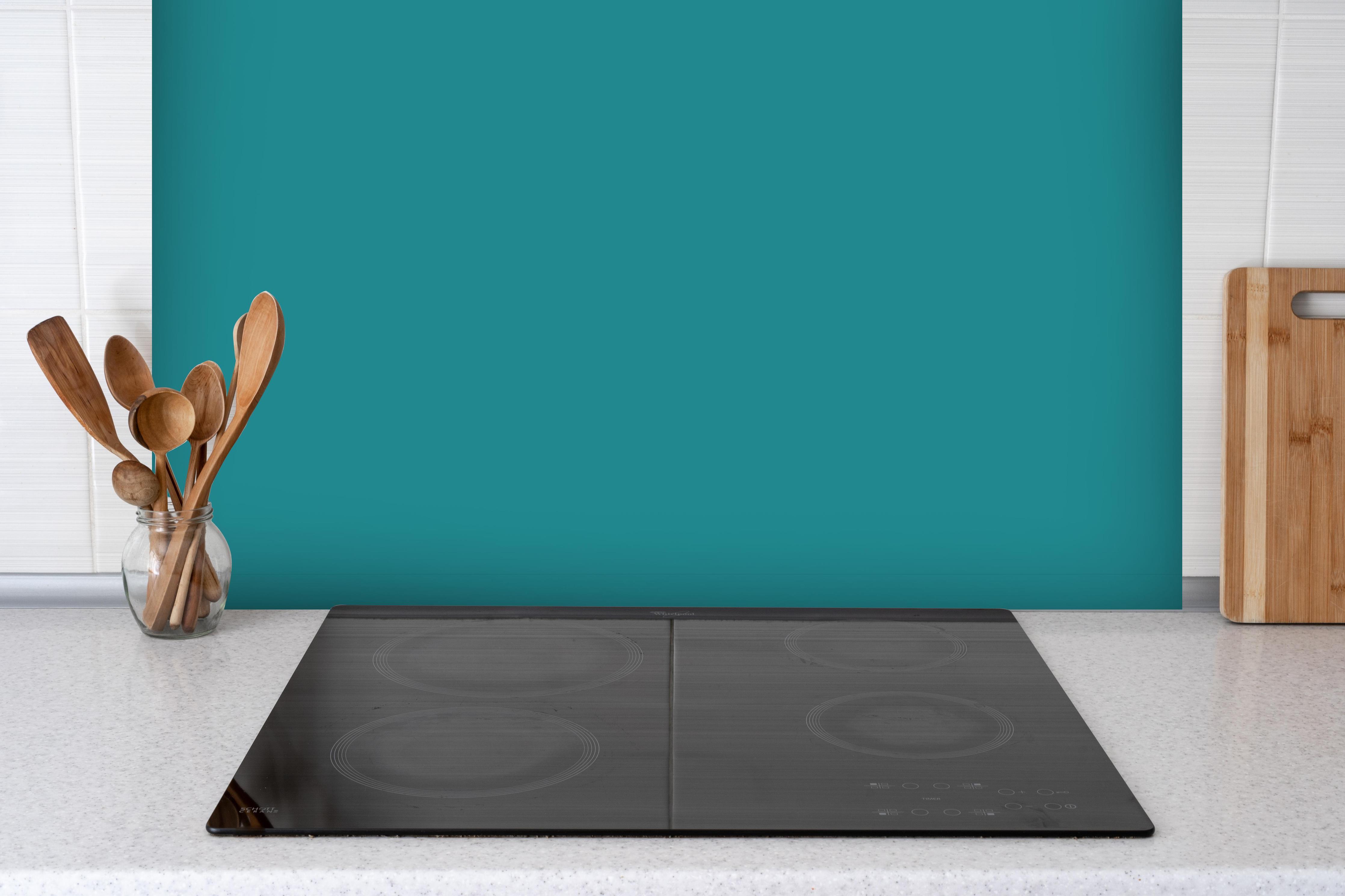 Spritzschutz - RAL 5018 (Türkisblau) hinter einem Cerankochfeld zwischen Holz-Kochutensilien