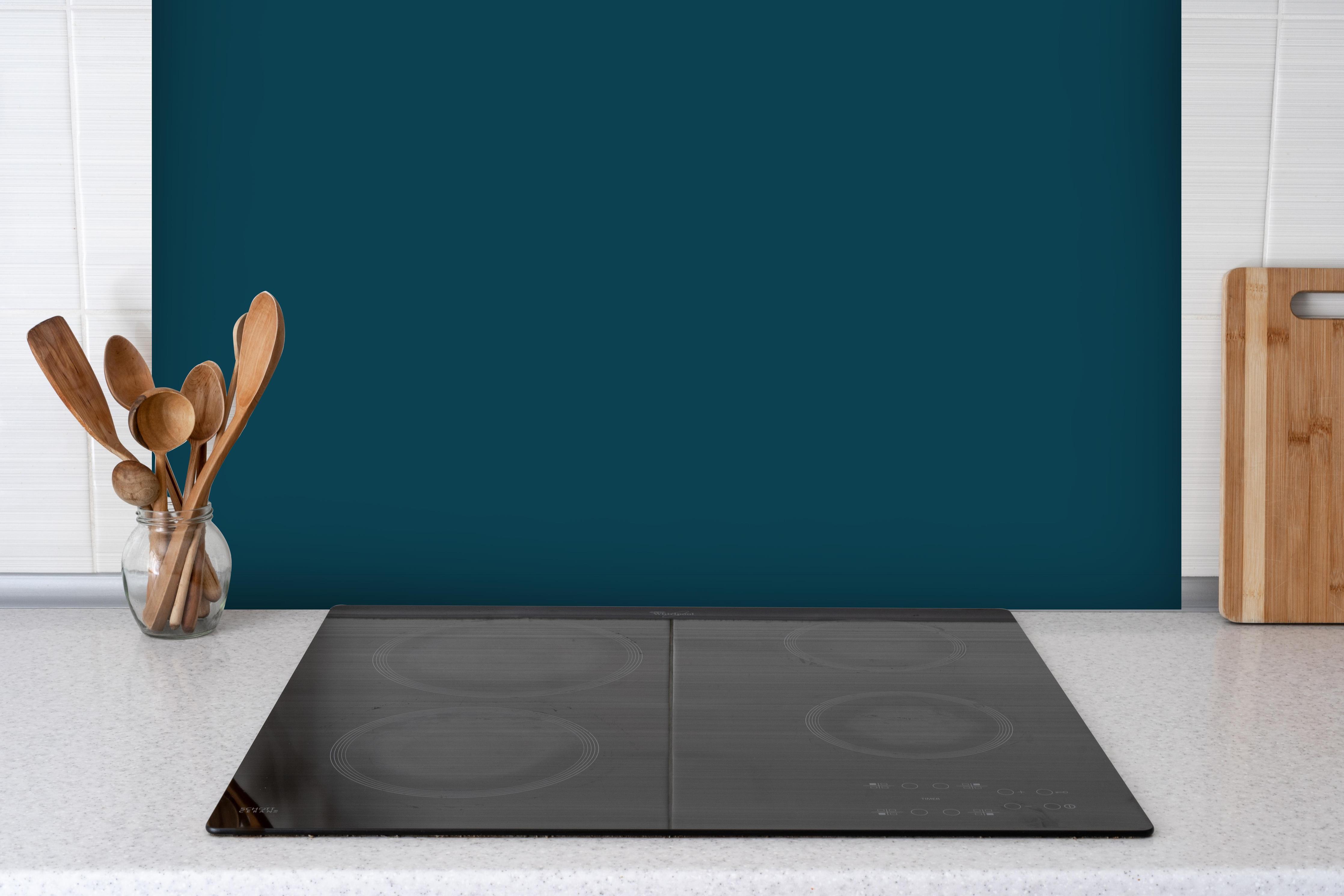 Spritzschutz - RAL 5020 (Ozeanblau) hinter einem Cerankochfeld zwischen Holz-Kochutensilien