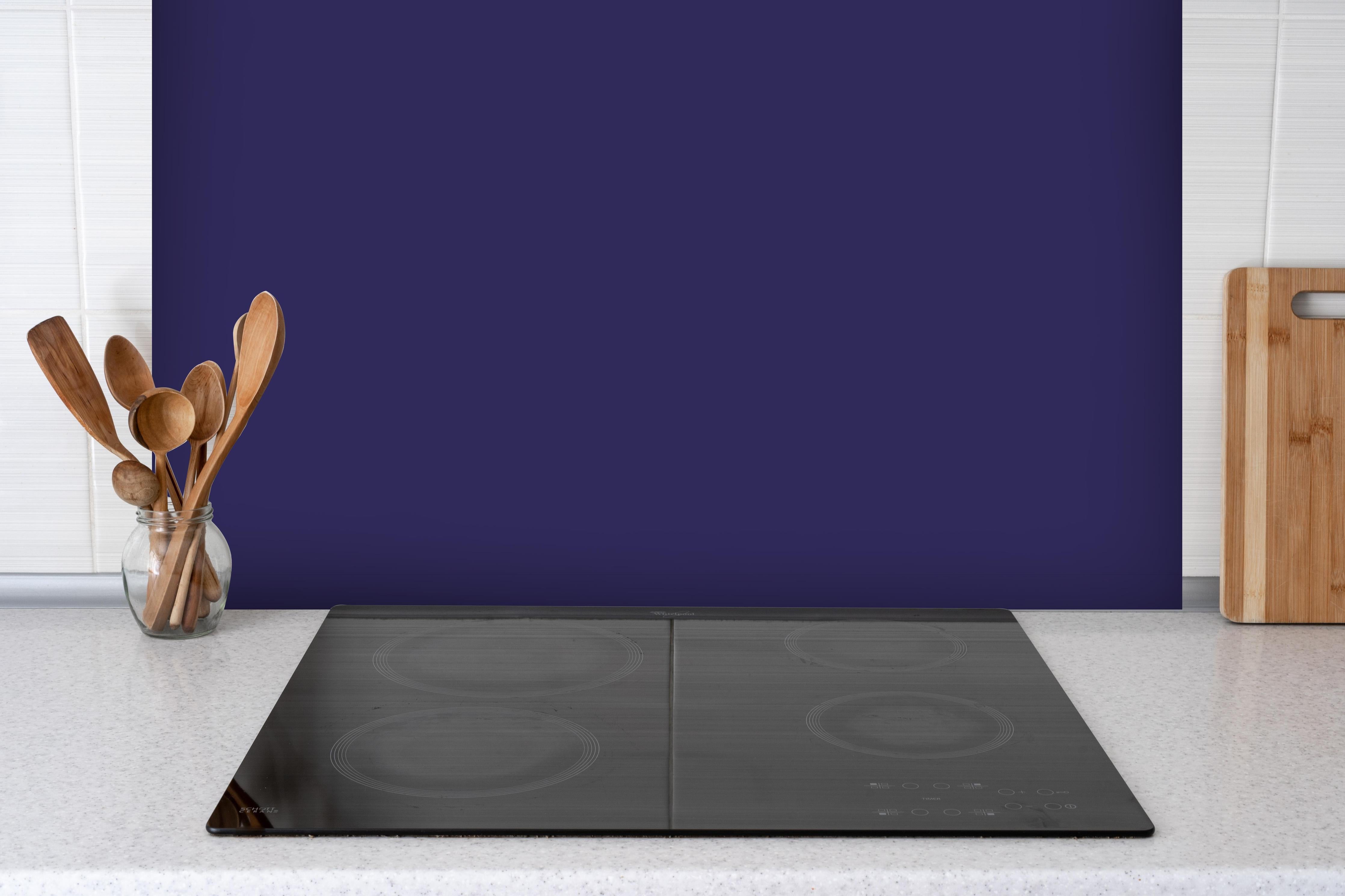 Spritzschutz - RAL 5022 (Nachtblau) hinter einem Cerankochfeld zwischen Holz-Kochutensilien