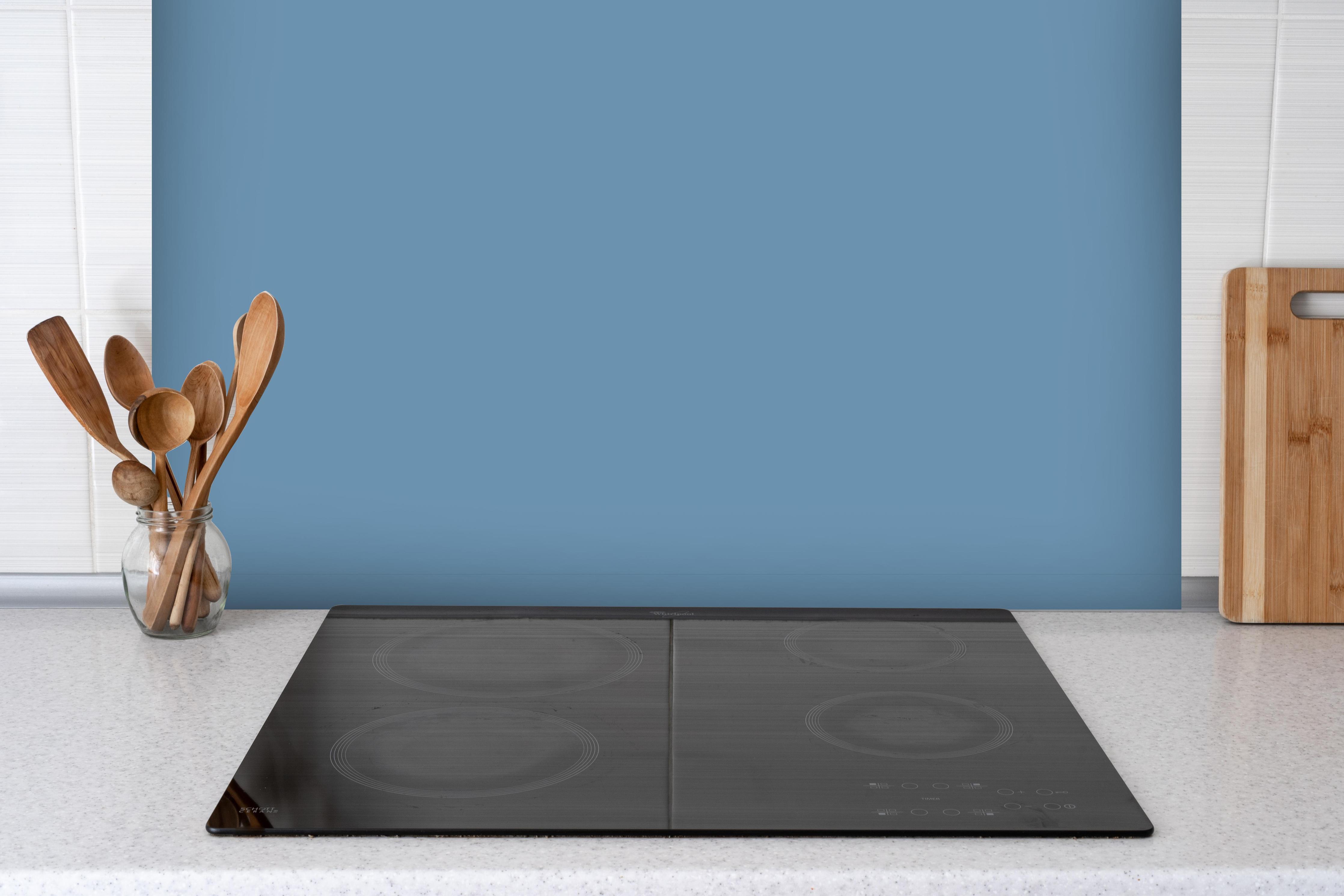 Spritzschutz - RAL 5024 (Pastellblau) hinter einem Cerankochfeld zwischen Holz-Kochutensilien