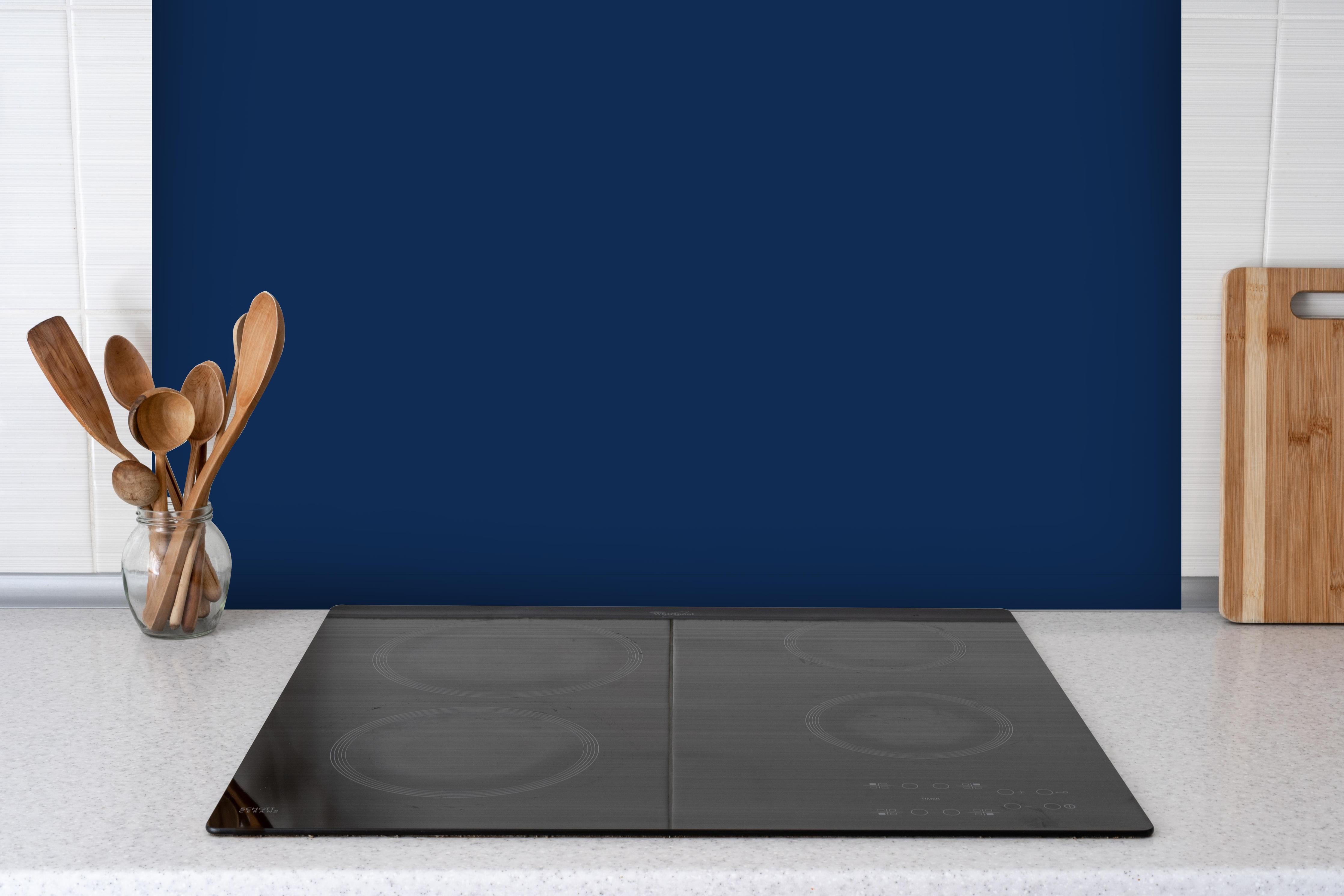 Spritzschutz - RAL 5026 (Perlnachtblau) hinter einem Cerankochfeld zwischen Holz-Kochutensilien