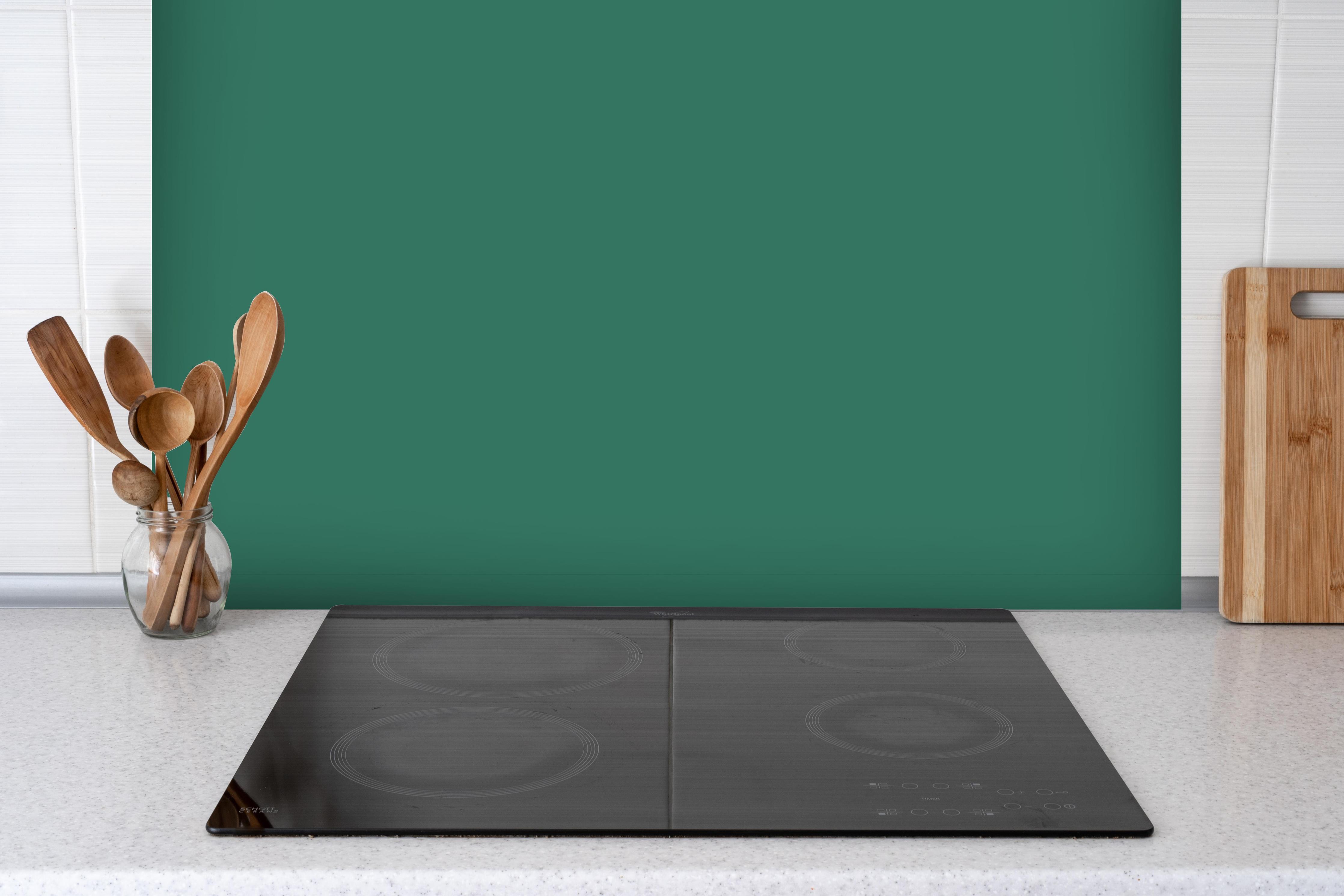 Spritzschutz - RAL 6000 (Patinagrün) hinter einem Cerankochfeld zwischen Holz-Kochutensilien