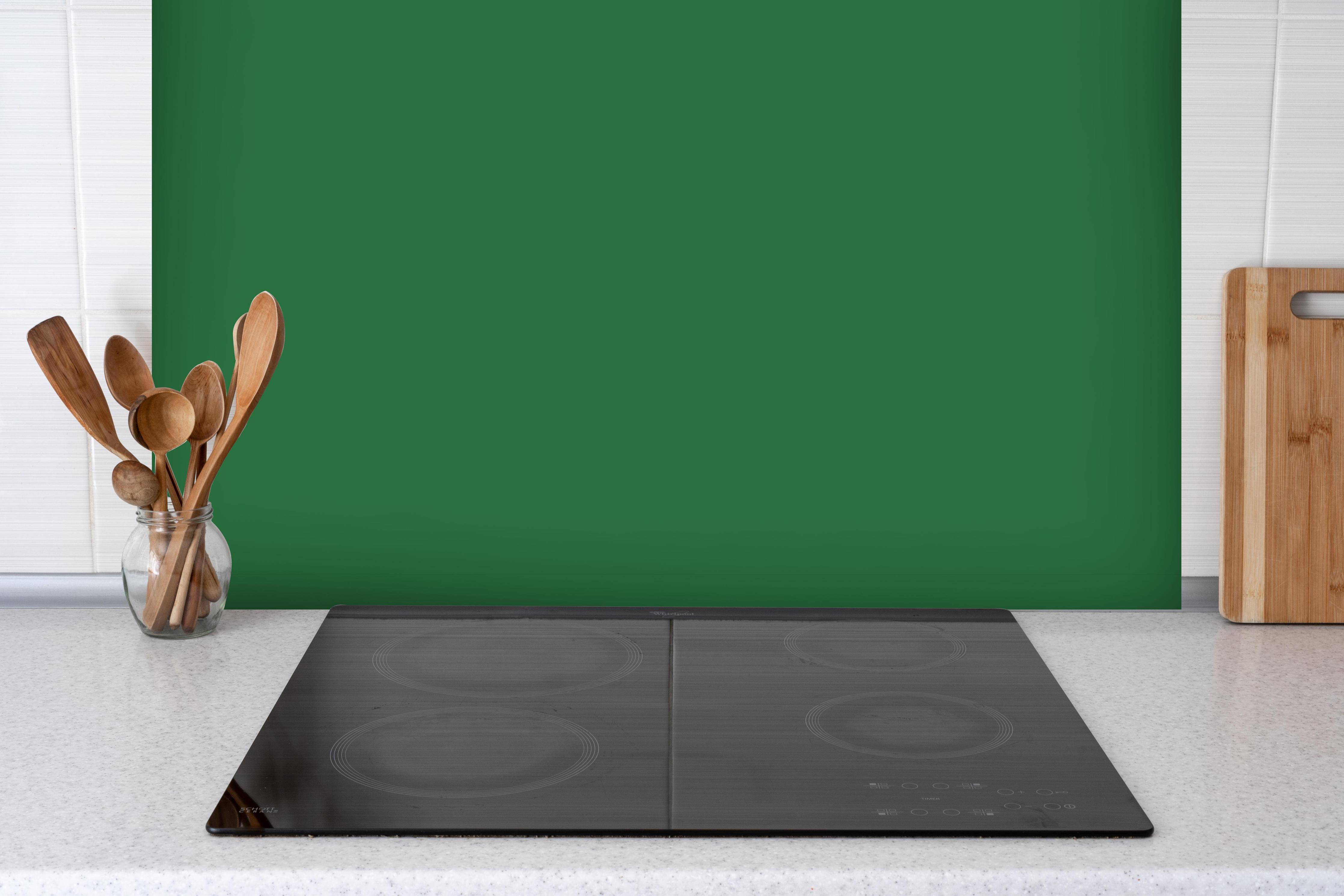 Spritzschutz - RAL 6001 (Smaragdgrün) hinter einem Cerankochfeld zwischen Holz-Kochutensilien