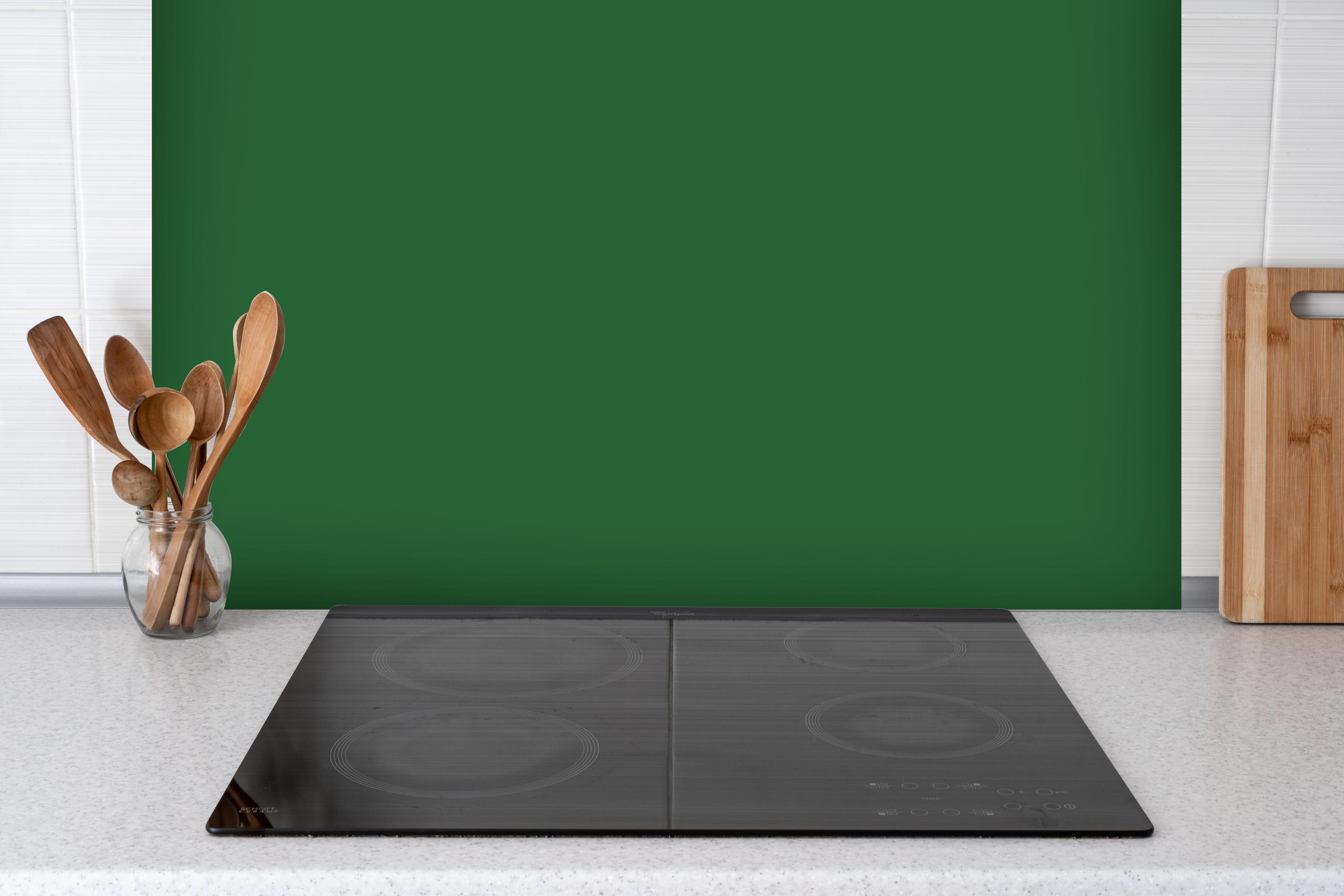 Spritzschutz - RAL 6002 (Laubgrün) hinter einem Cerankochfeld zwischen Holz-Kochutensilien