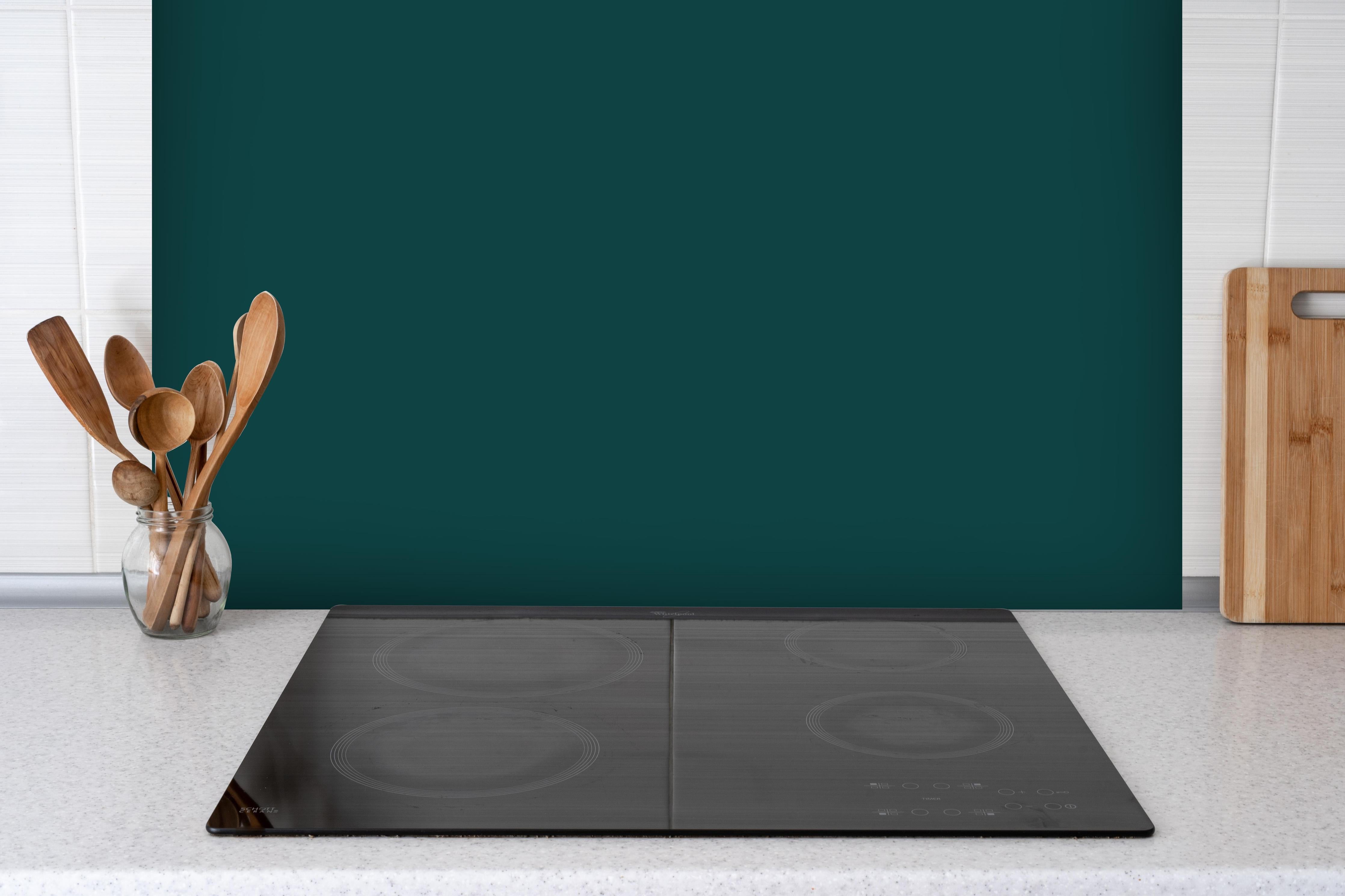 Spritzschutz - RAL 6004 (Blaugrün) hinter einem Cerankochfeld zwischen Holz-Kochutensilien