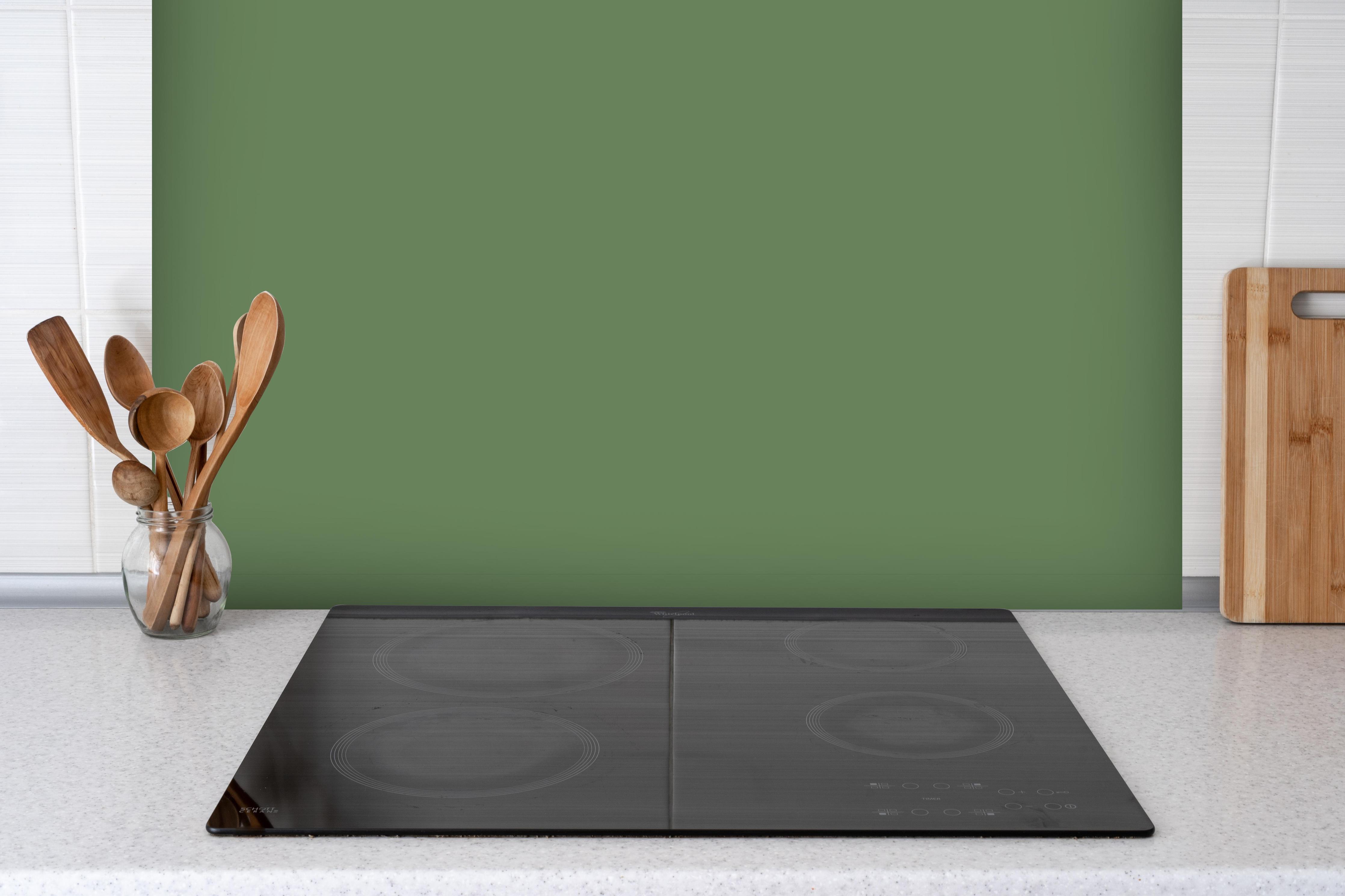 Spritzschutz - RAL 6011 (Reseda grün) hinter einem Cerankochfeld zwischen Holz-Kochutensilien