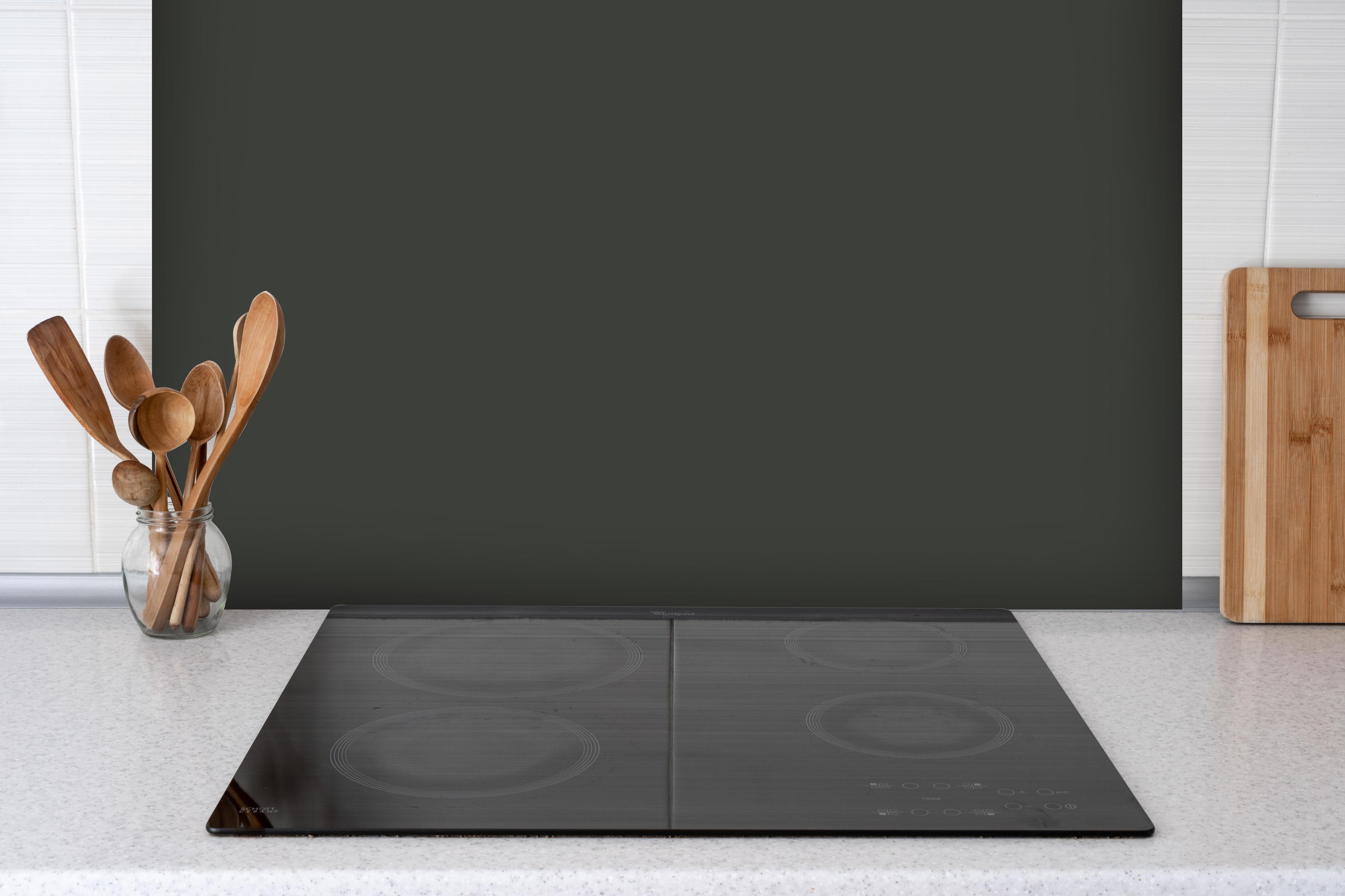 Spritzschutz - RAL 6015 (Schwarzoliv) hinter einem Cerankochfeld zwischen Holz-Kochutensilien