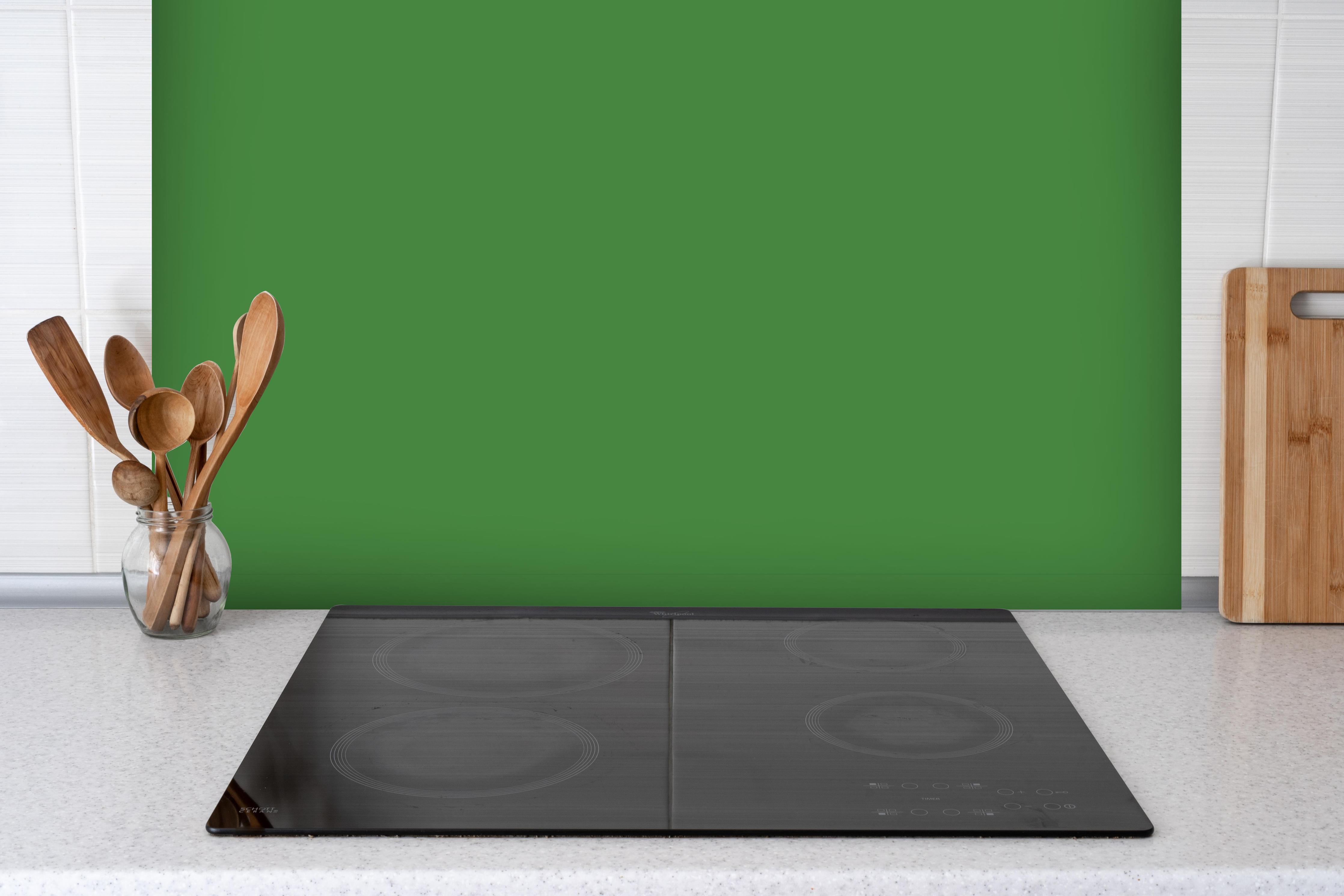 Spritzschutz - RAL 6017 (Maigrün) hinter einem Cerankochfeld zwischen Holz-Kochutensilien