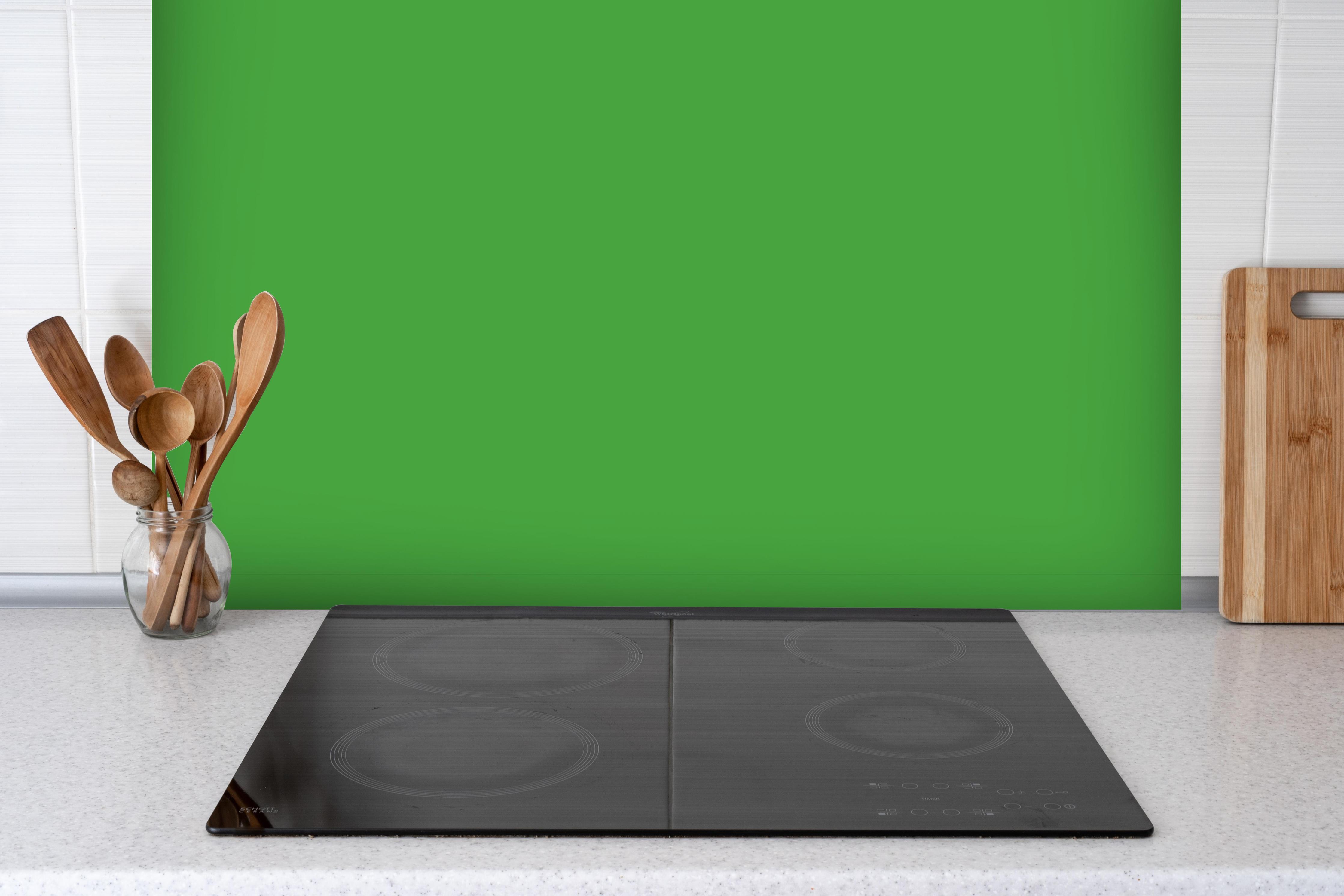 Spritzschutz - RAL 6018 (Gelbgrün) hinter einem Cerankochfeld zwischen Holz-Kochutensilien