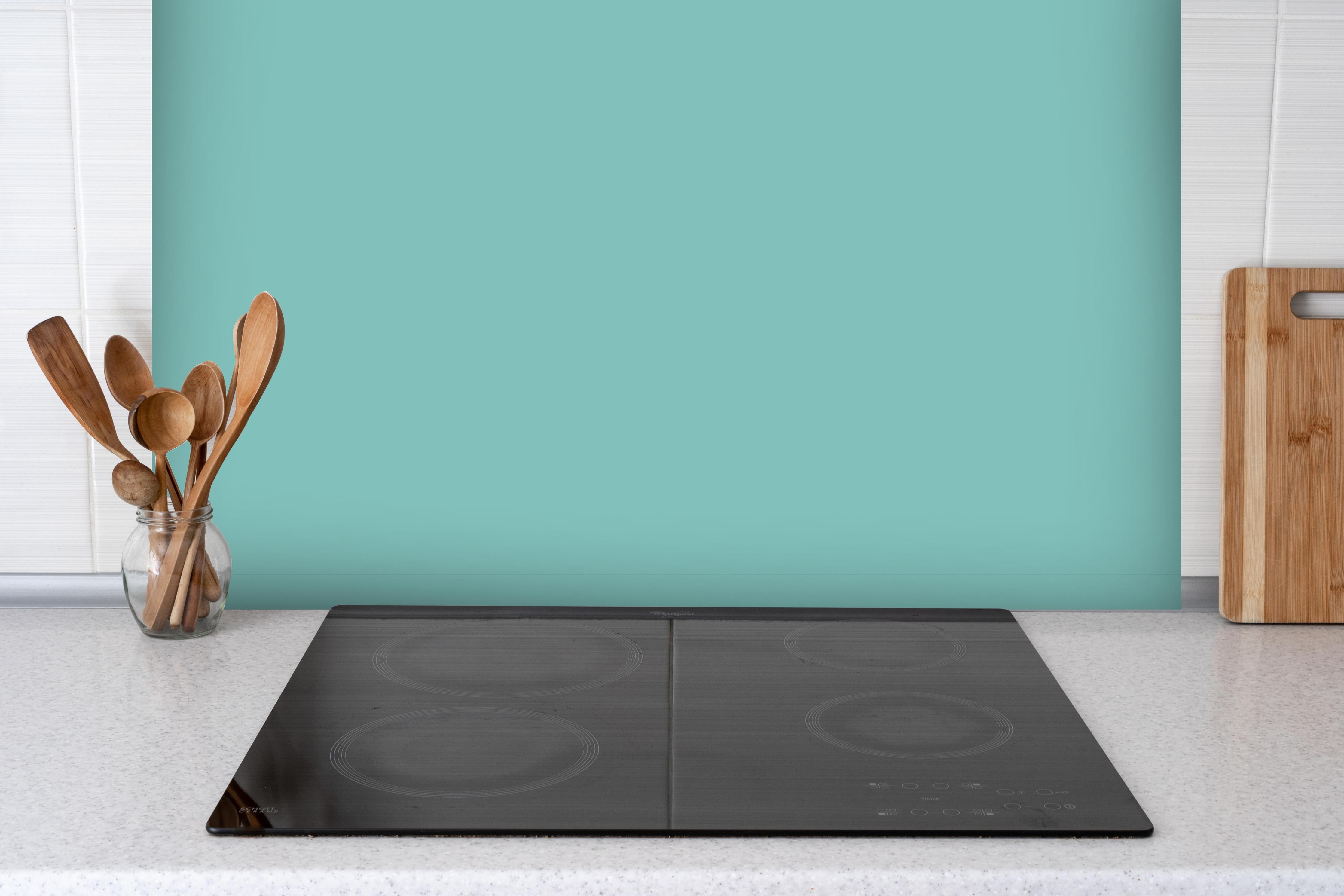 Spritzschutz - RAL 6027 (Hellgrün) hinter einem Cerankochfeld zwischen Holz-Kochutensilien