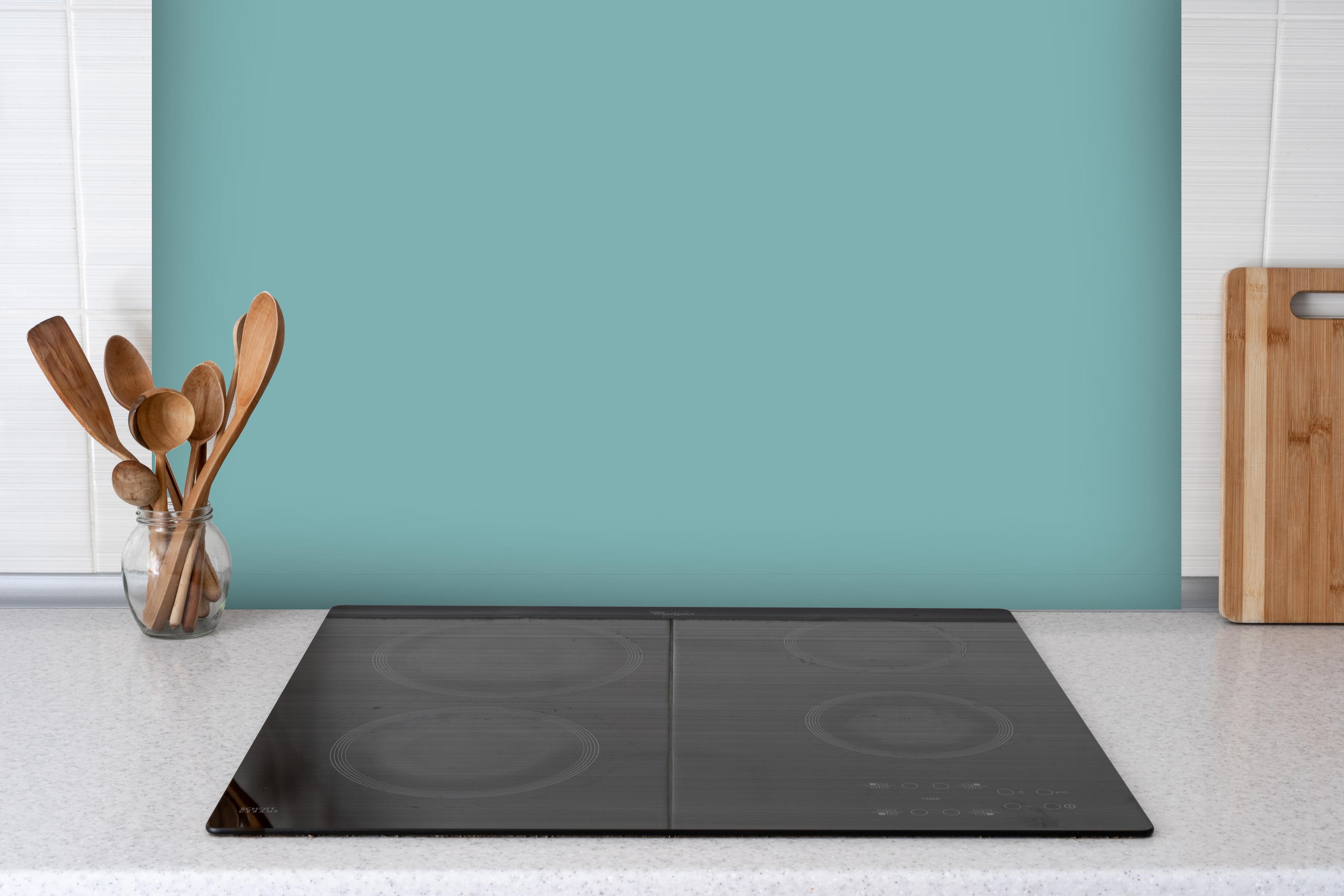 Spritzschutz - RAL 6034 (Pastell-Türkis) hinter einem Cerankochfeld zwischen Holz-Kochutensilien