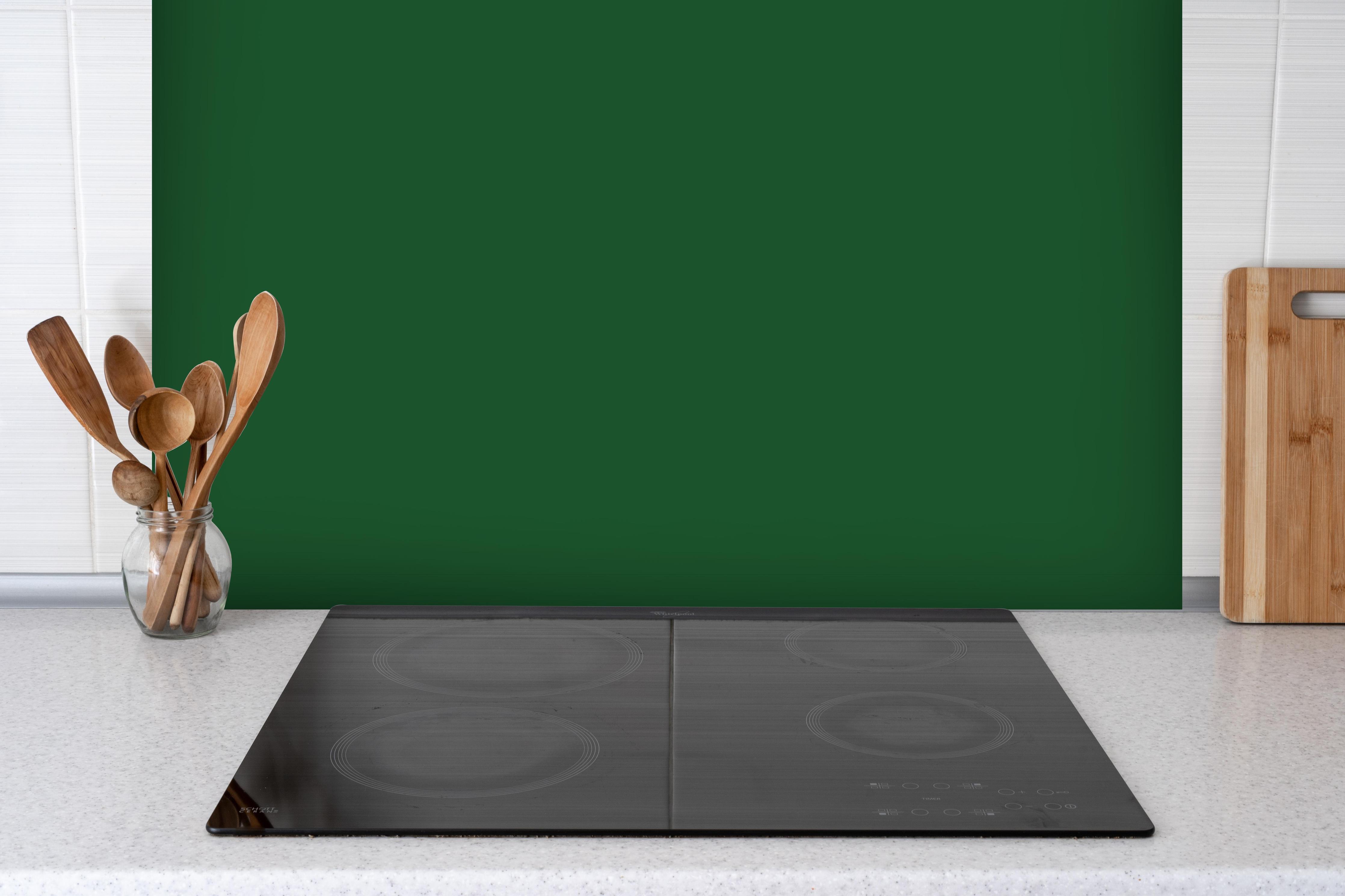 Spritzschutz - RAL 6035 (Perlgrün) hinter einem Cerankochfeld zwischen Holz-Kochutensilien