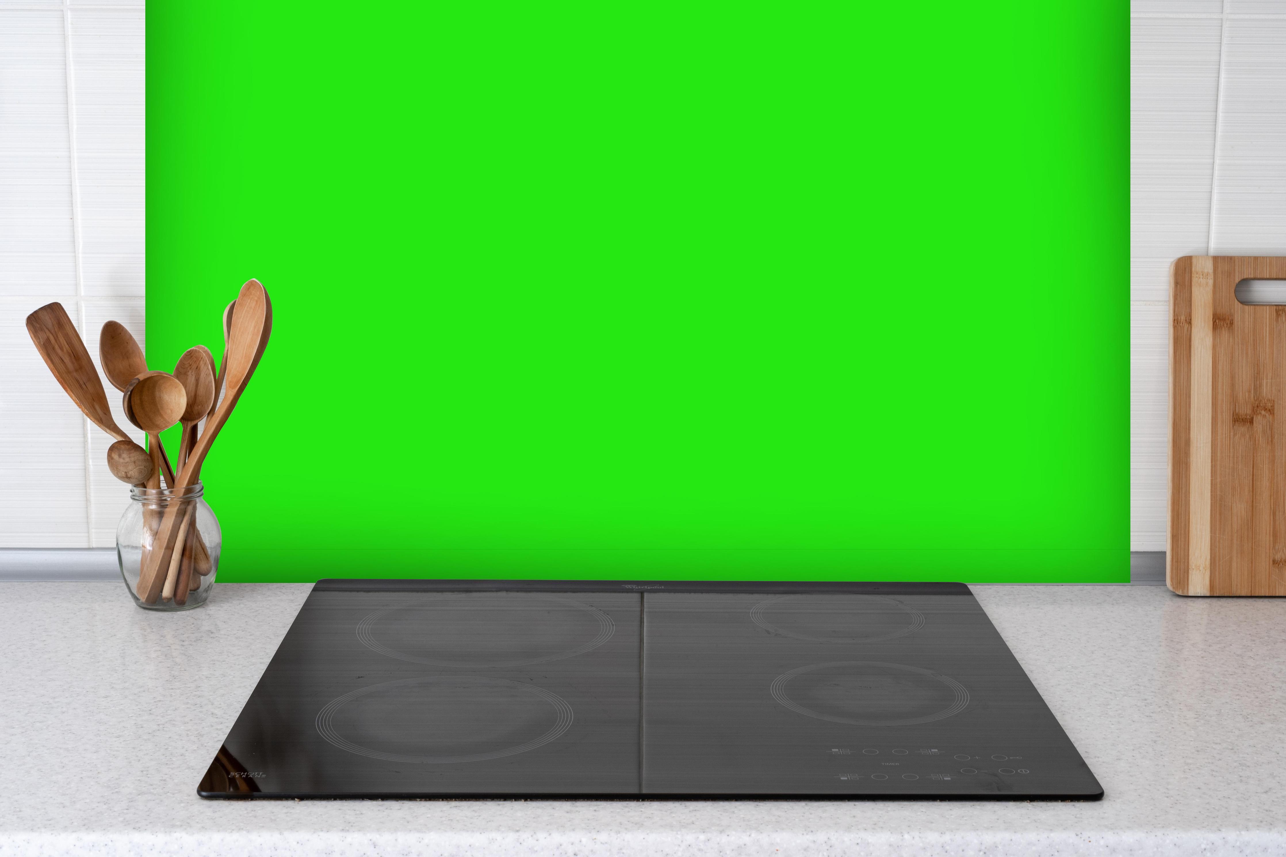 Spritzschutz - RAL 6037 (Reines Grün) hinter einem Cerankochfeld zwischen Holz-Kochutensilien