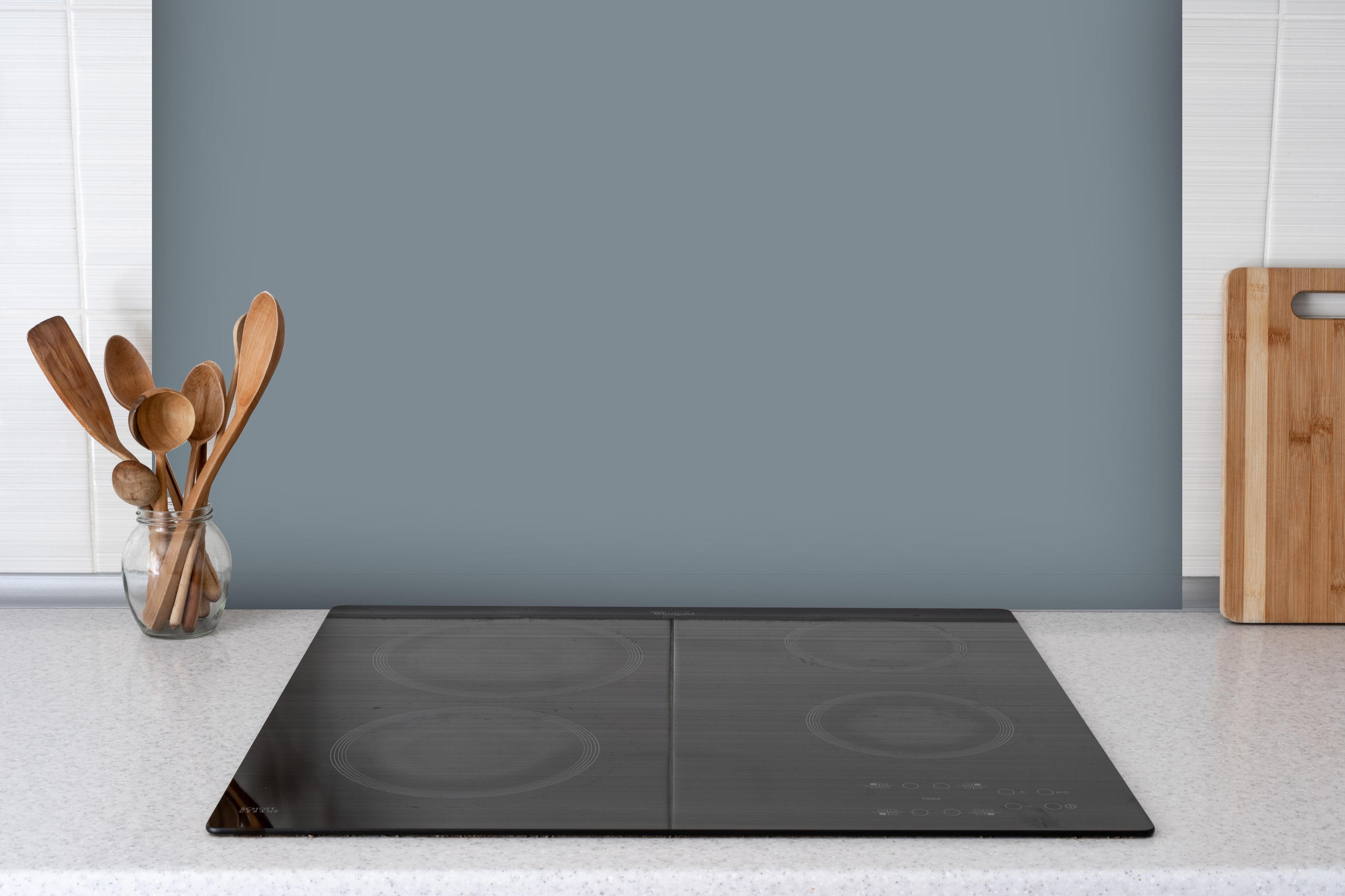 Spritzschutz - RAL 7000 (Eichhörnchengrau) hinter einem Cerankochfeld zwischen Holz-Kochutensilien