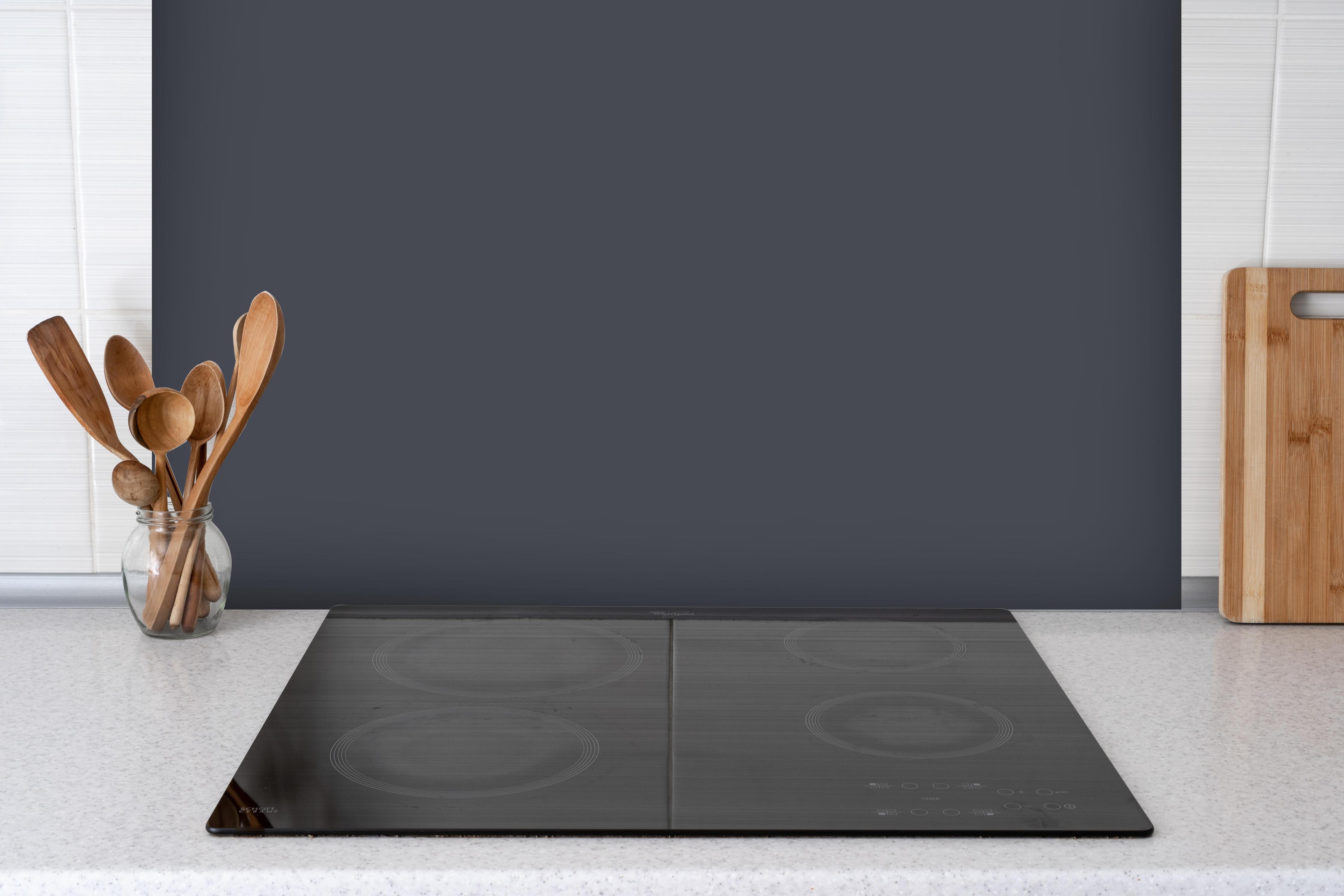 Spritzschutz - RAL 7024 (Graphitgrau) hinter einem Cerankochfeld zwischen Holz-Kochutensilien