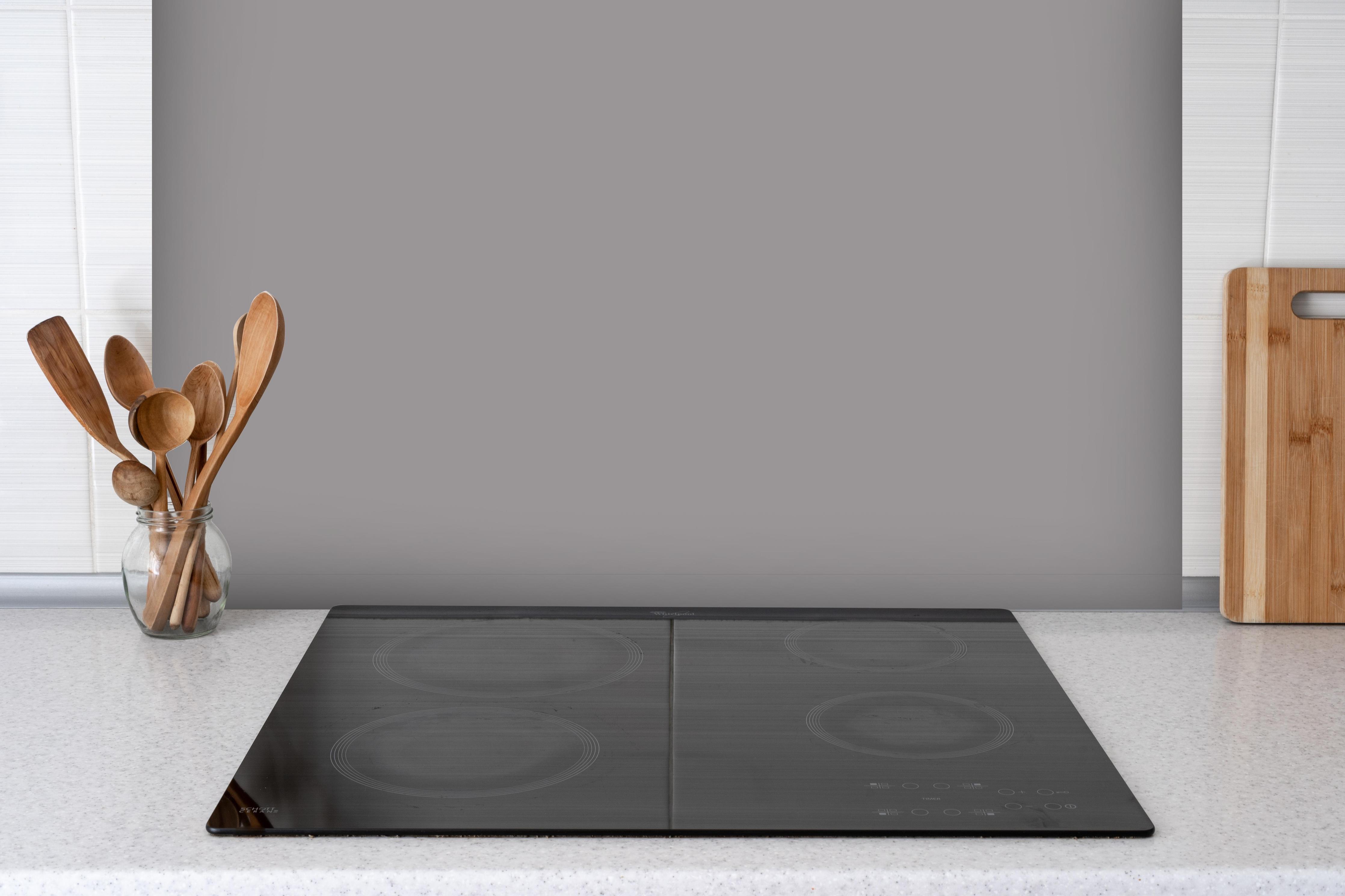 Spritzschutz - RAL 7036 (Platingrau) hinter einem Cerankochfeld zwischen Holz-Kochutensilien