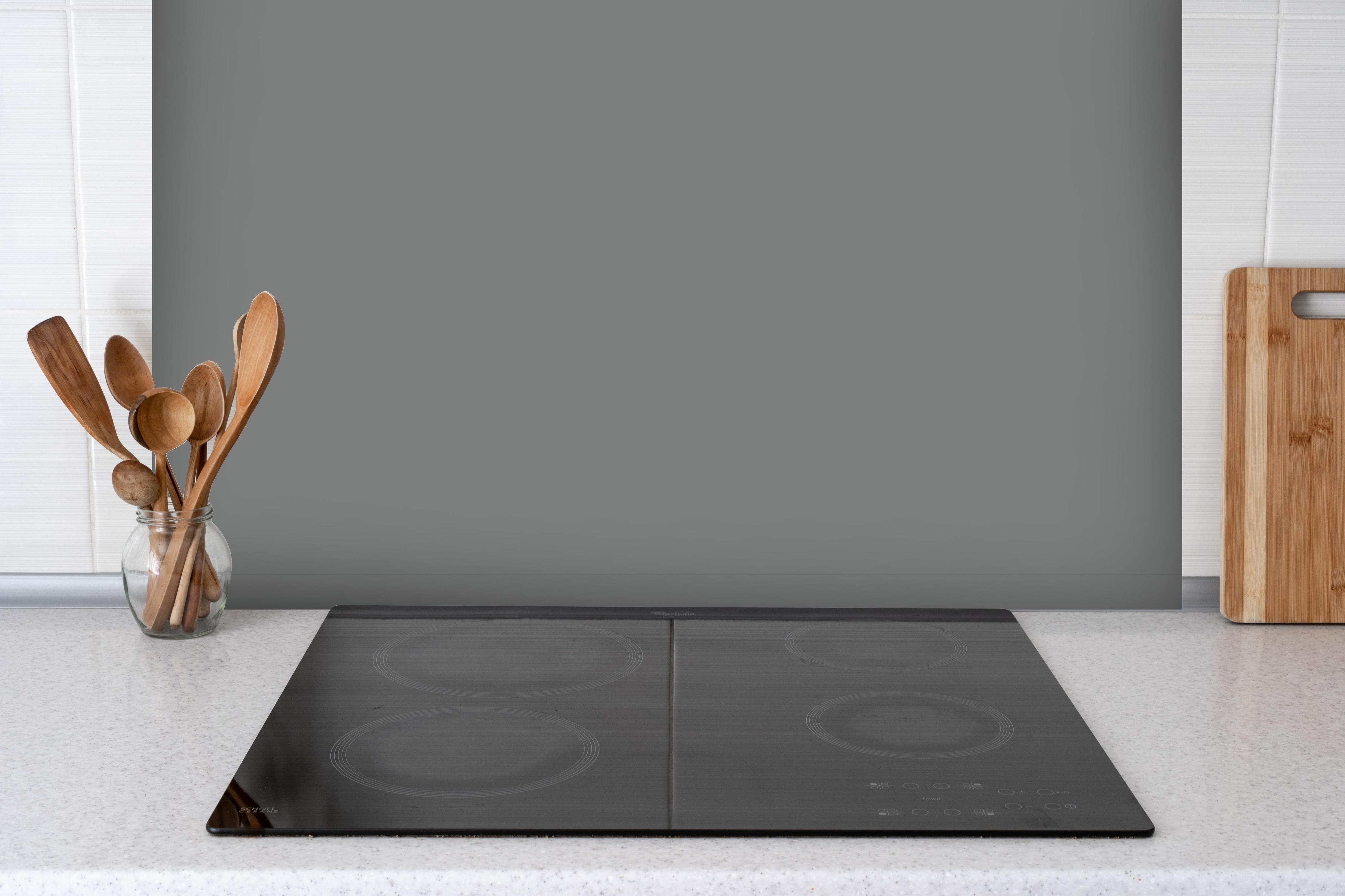Spritzschutz - RAL 7037 (Staubiges Grau) hinter einem Cerankochfeld zwischen Holz-Kochutensilien