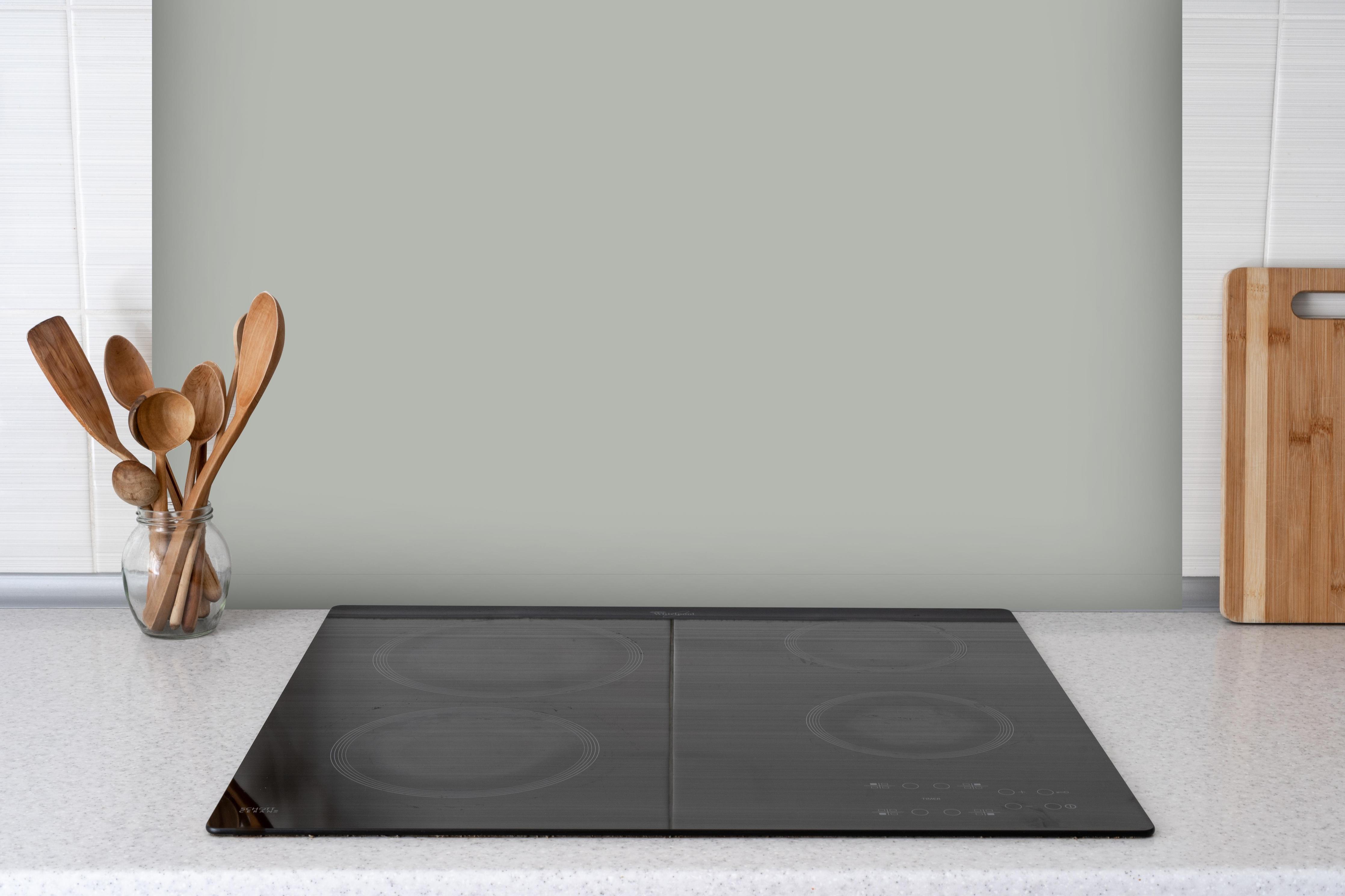 Spritzschutz - RAL 7038 (Achatgrau) hinter einem Cerankochfeld zwischen Holz-Kochutensilien