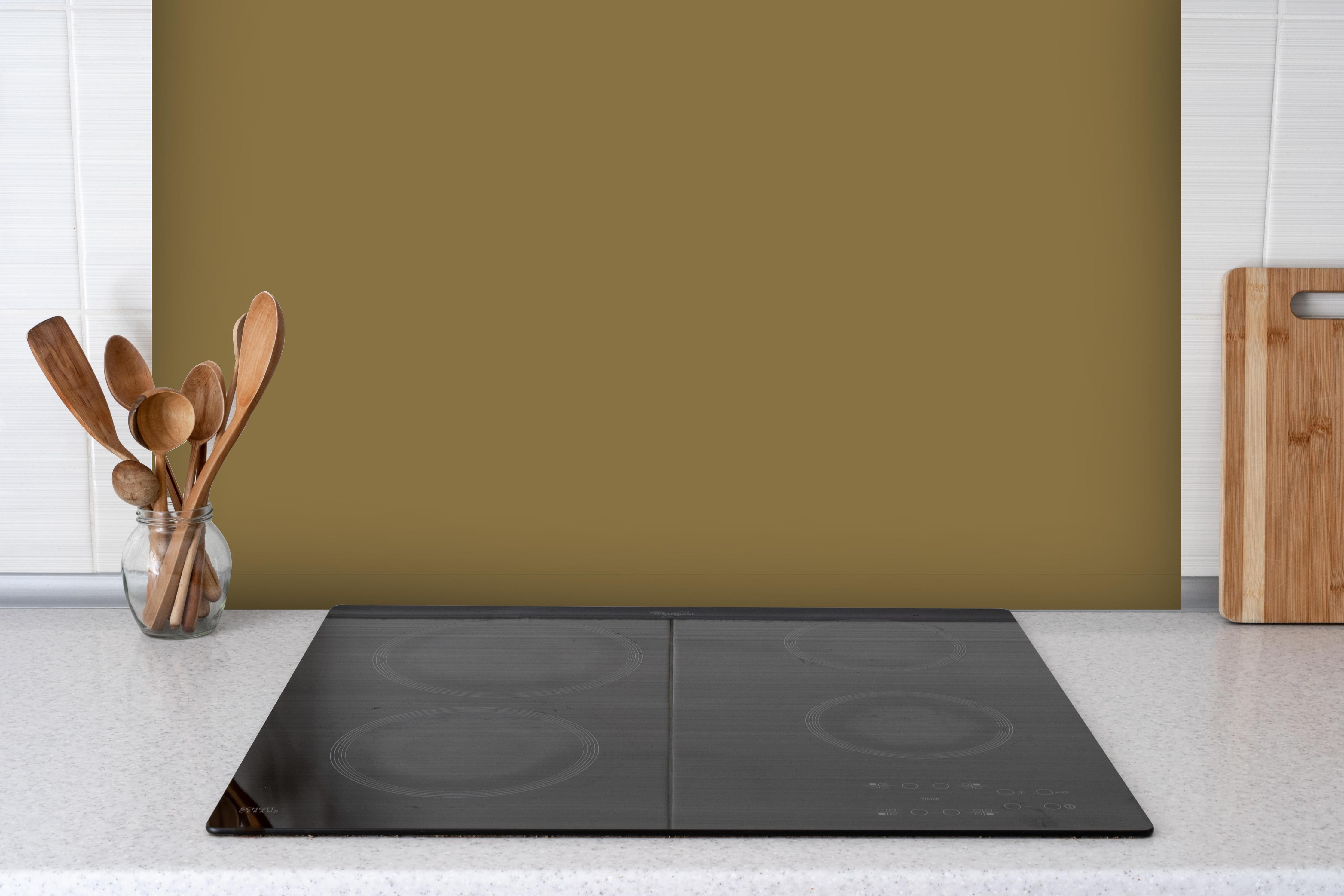Spritzschutz - RAL 8000 (Grünbraun) hinter einem Cerankochfeld zwischen Holz-Kochutensilien