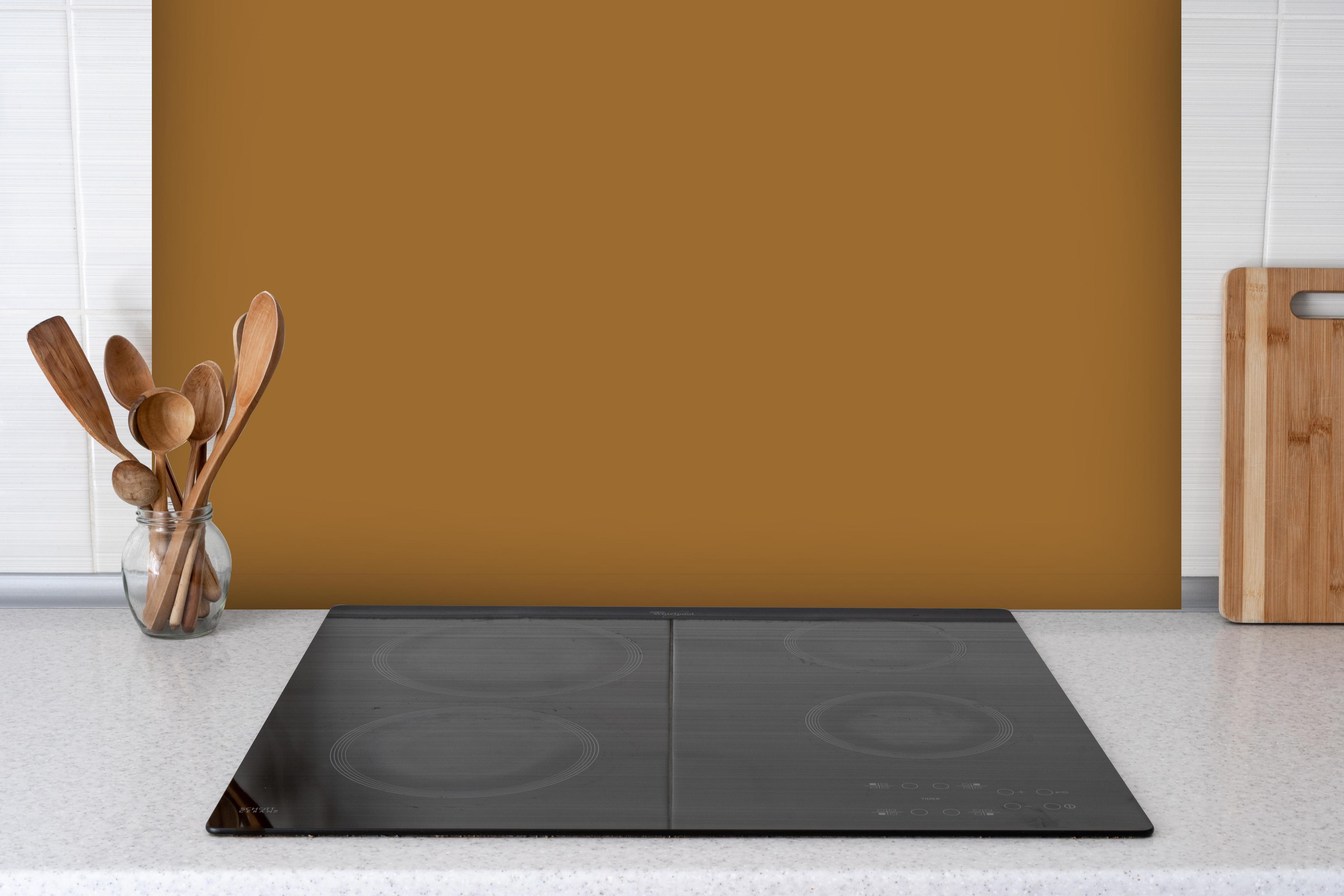 Spritzschutz - RAL 8001 (Ockerbraun) hinter einem Cerankochfeld zwischen Holz-Kochutensilien