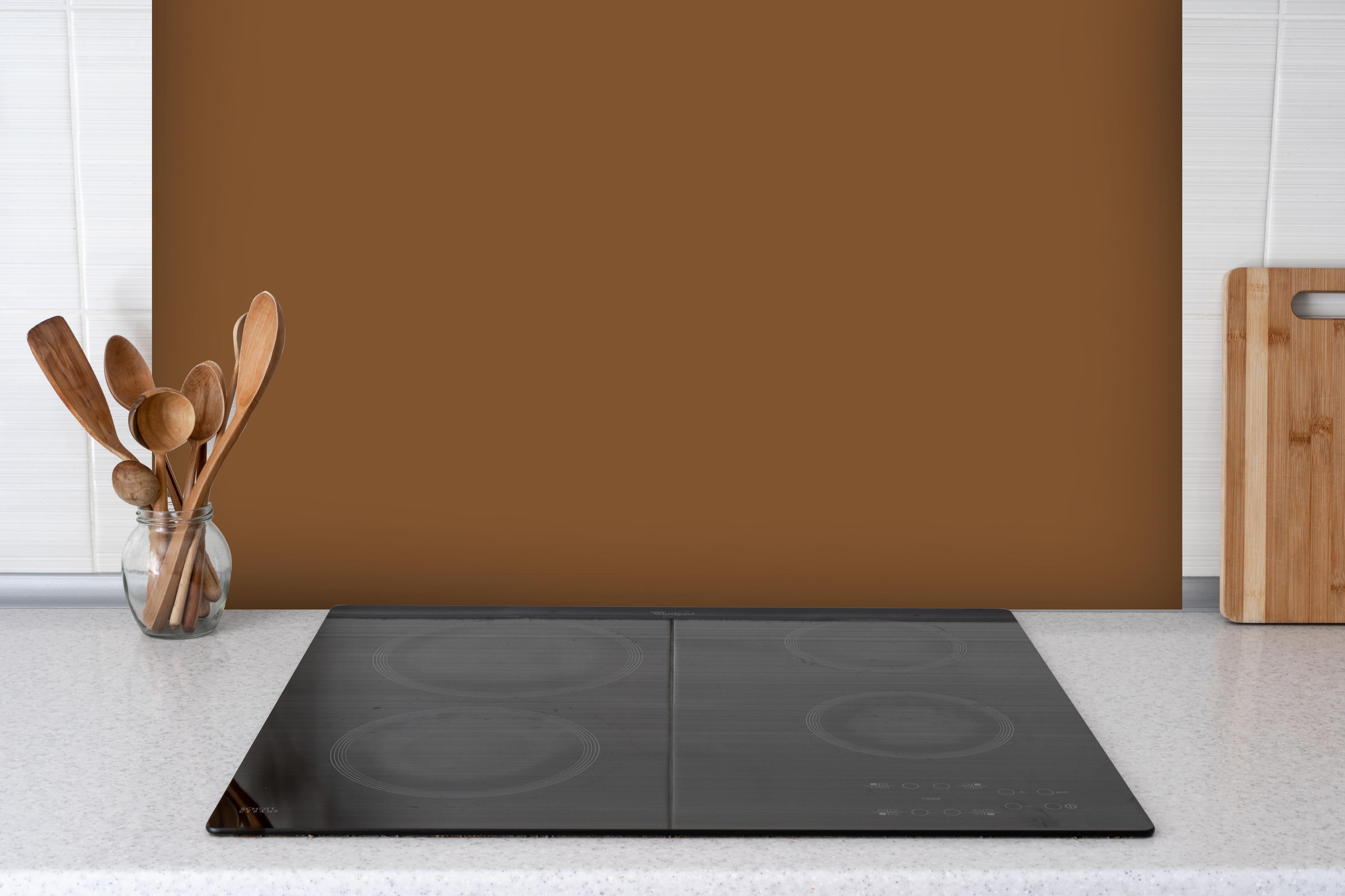Spritzschutz - RAL 8003 (Lehm-Braun) hinter einem Cerankochfeld zwischen Holz-Kochutensilien